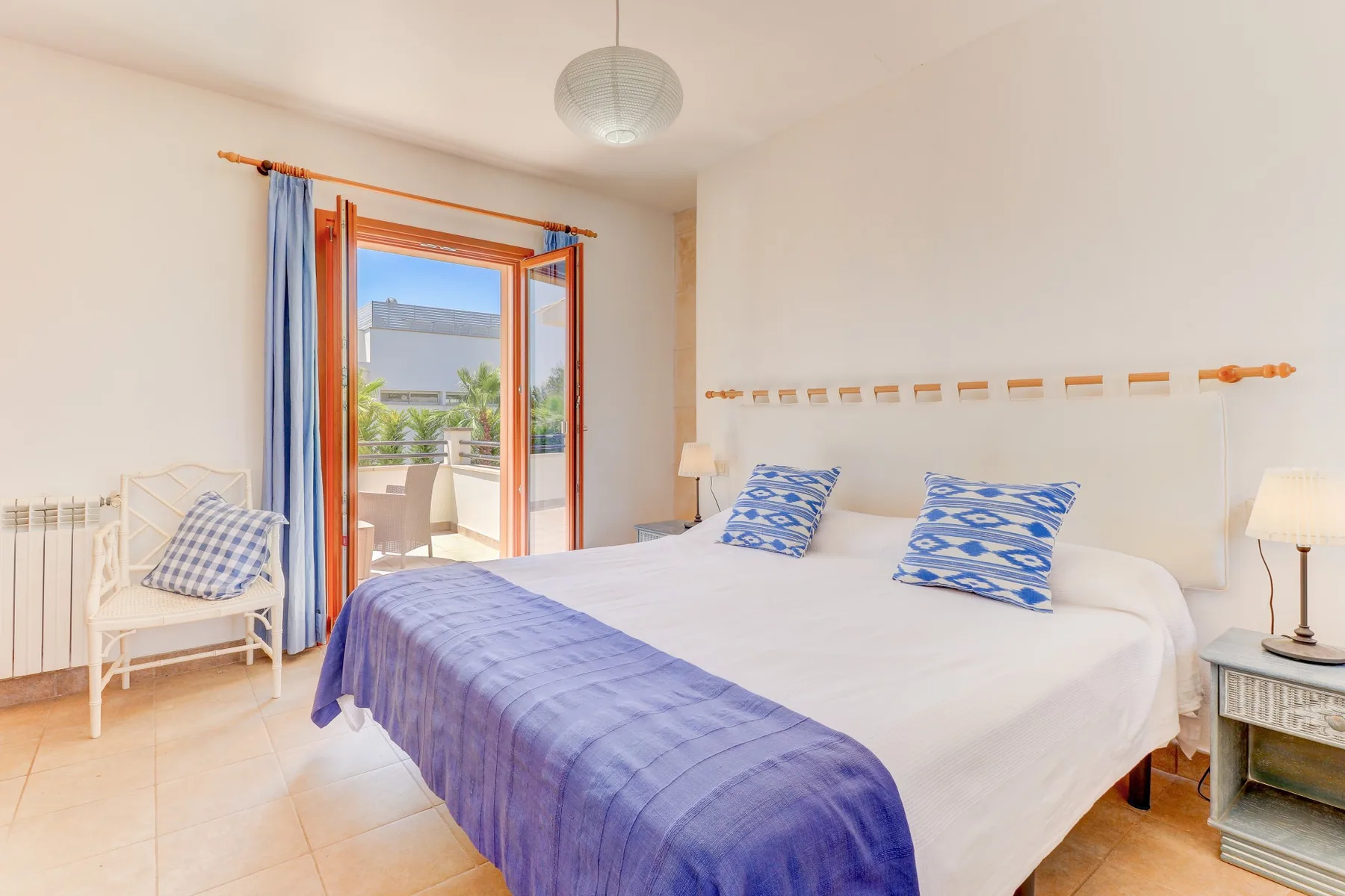 A bright bedroom with a large bed and an open doorway to a balcony.