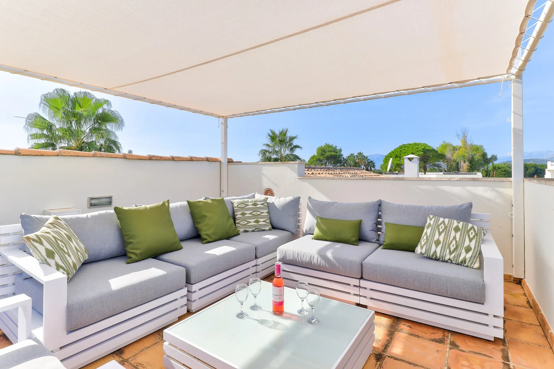 A covered outdoor seating area with gray cushions and a low table.
