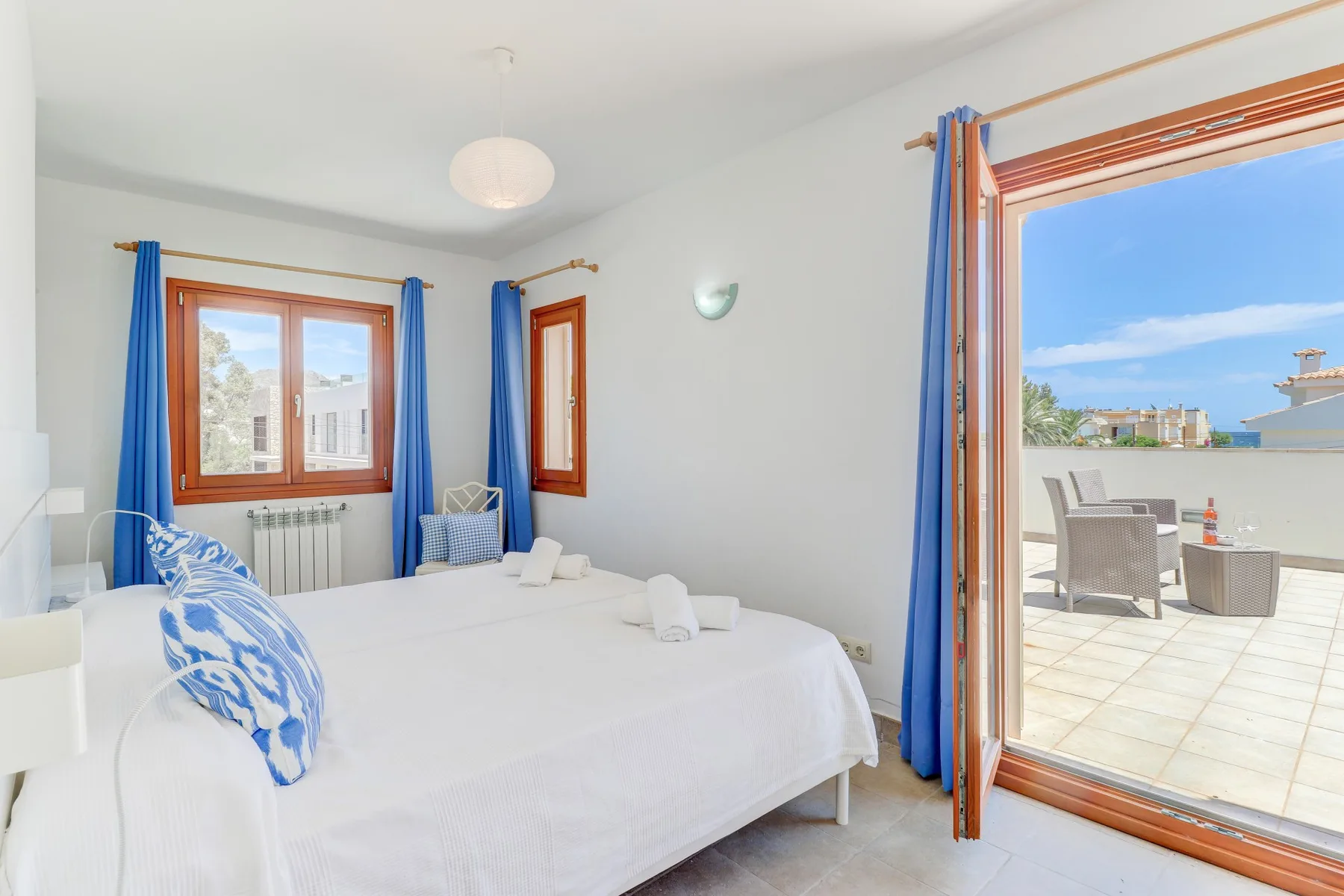 A bright bedroom opens onto a terrace through wide glass doors.