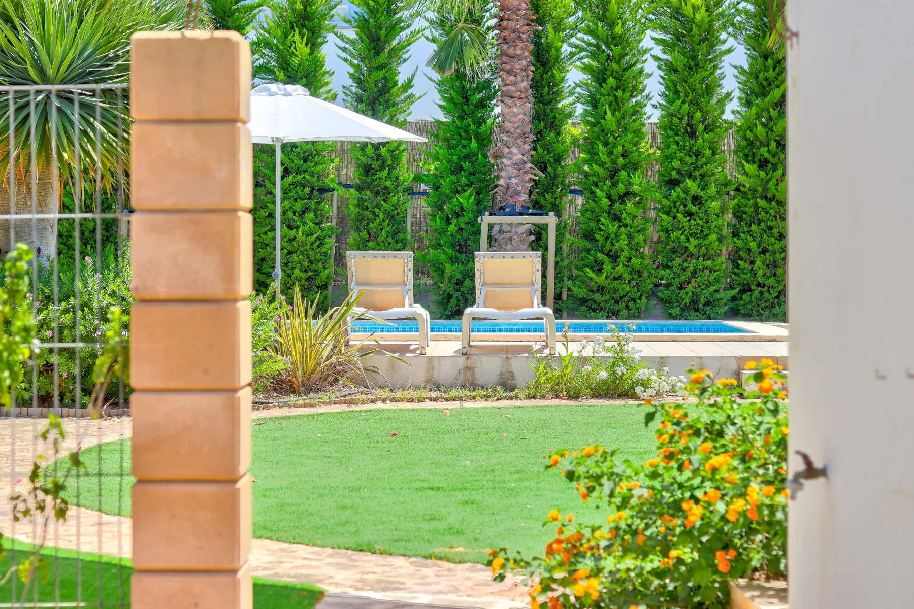 A landscaped garden with a lawn, swimming pool, and outdoor seating.