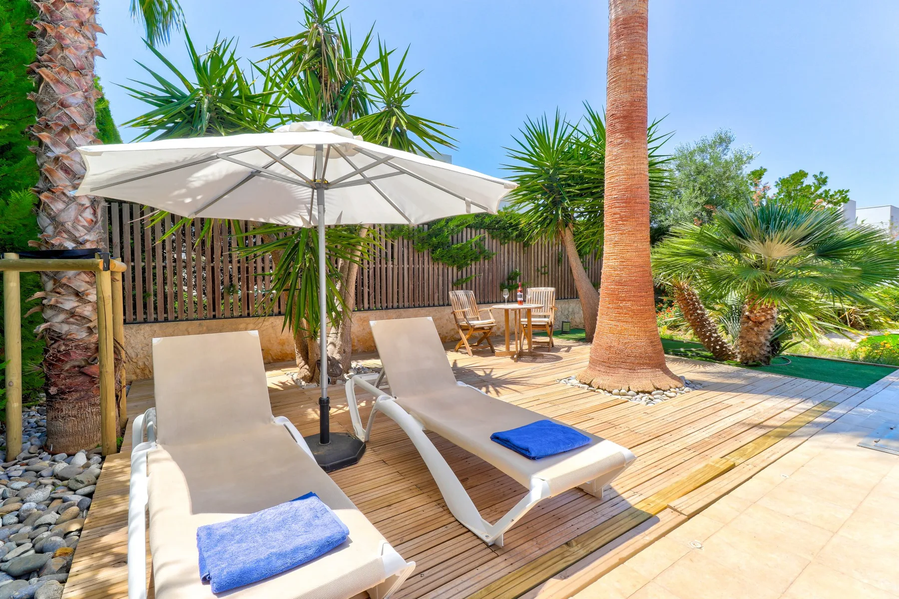 An outdoor poolside seating area with lounge chairs beneath a white umbrella.