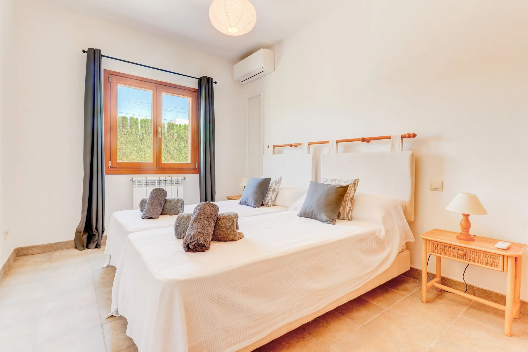 A bright bedroom with a large bed beneath a window.