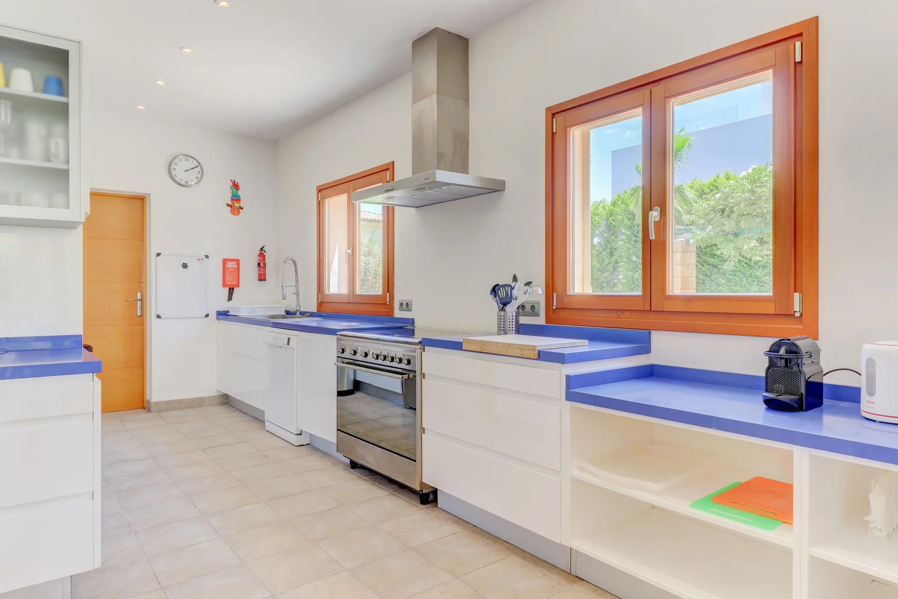 A bright kitchen with blue countertops, a stove, and wooden-framed windows.