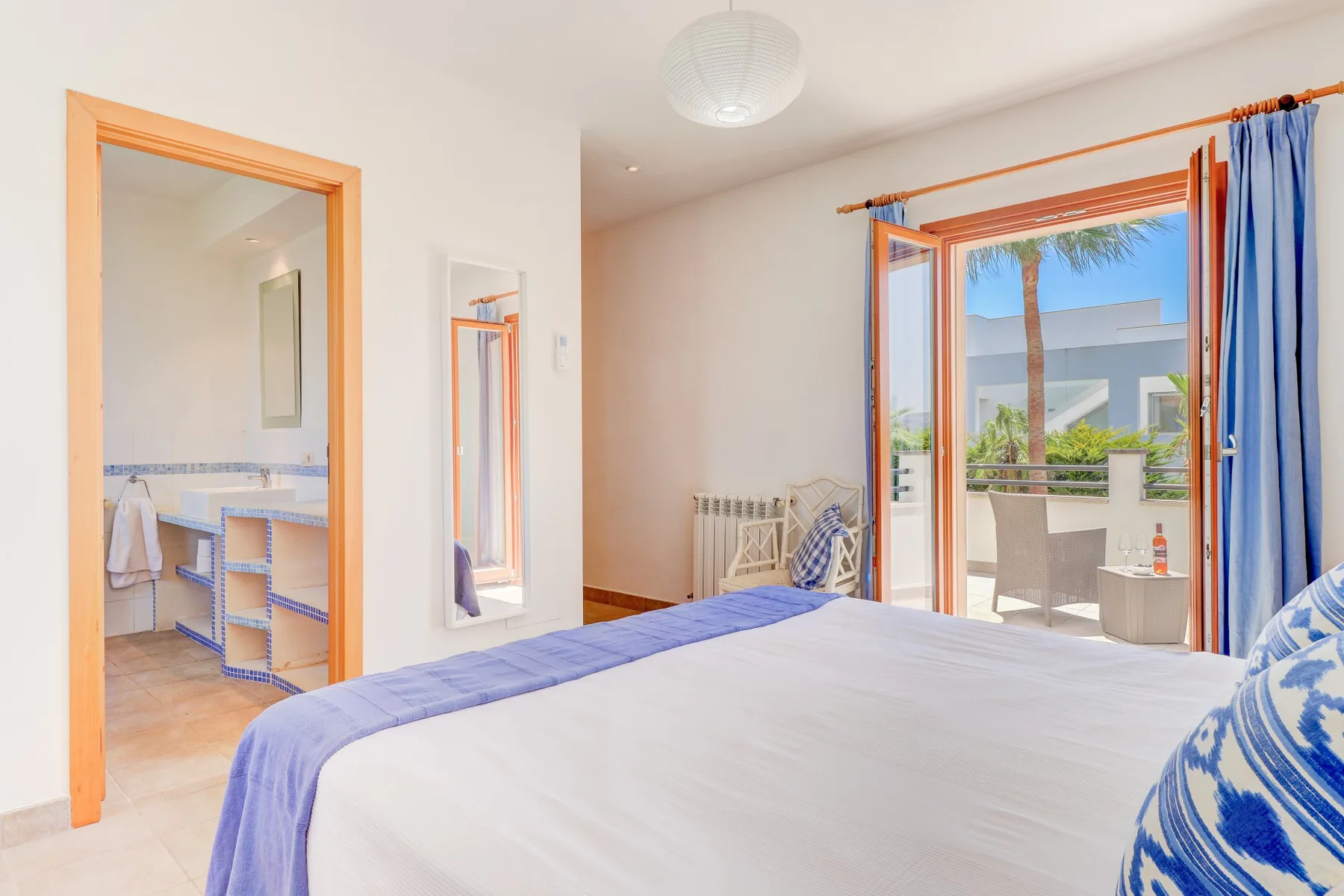 A bedroom with a bed and open doors leading to a balcony.