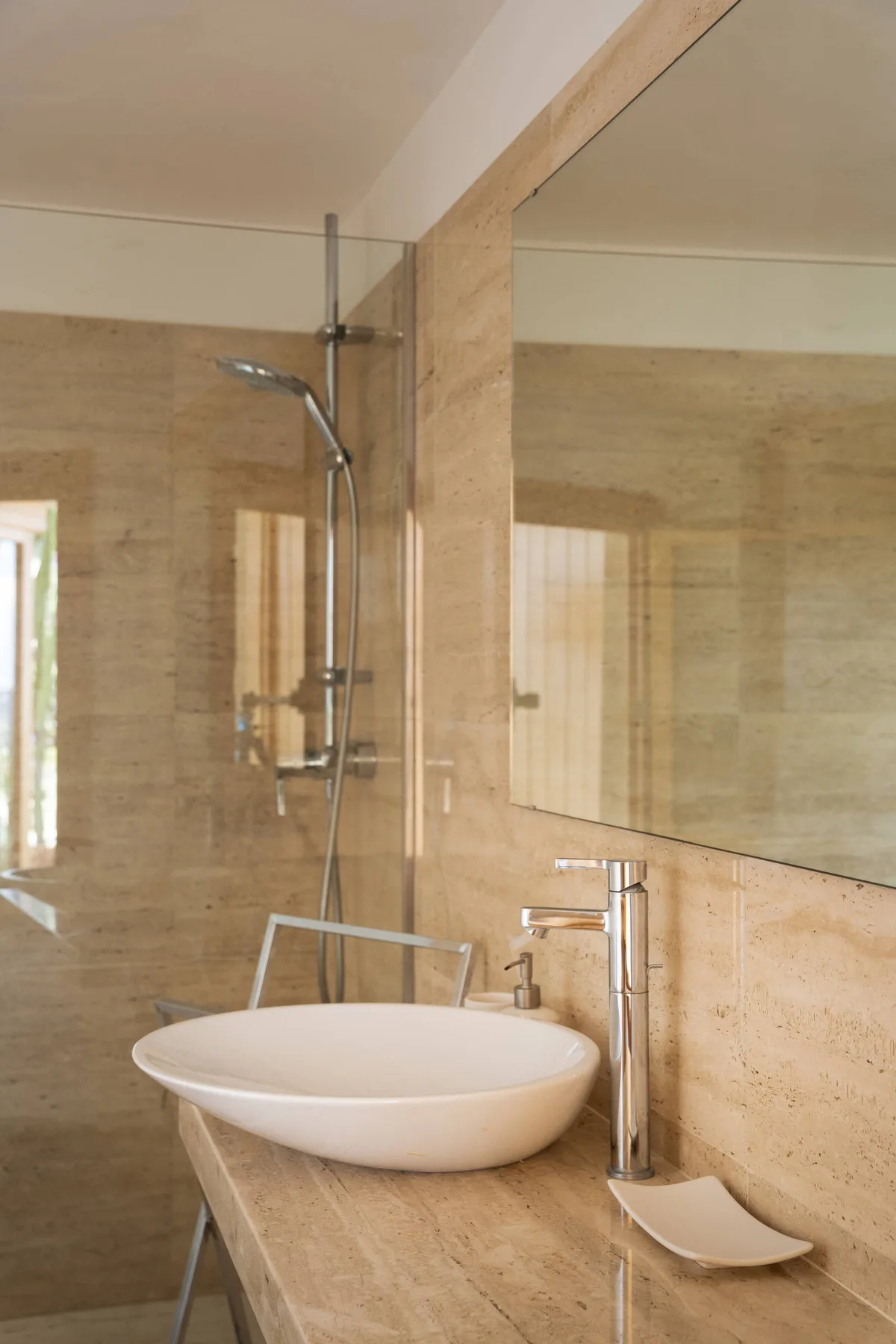 Un tocador de baño con lavabo de recipiente y una ducha al fondo.