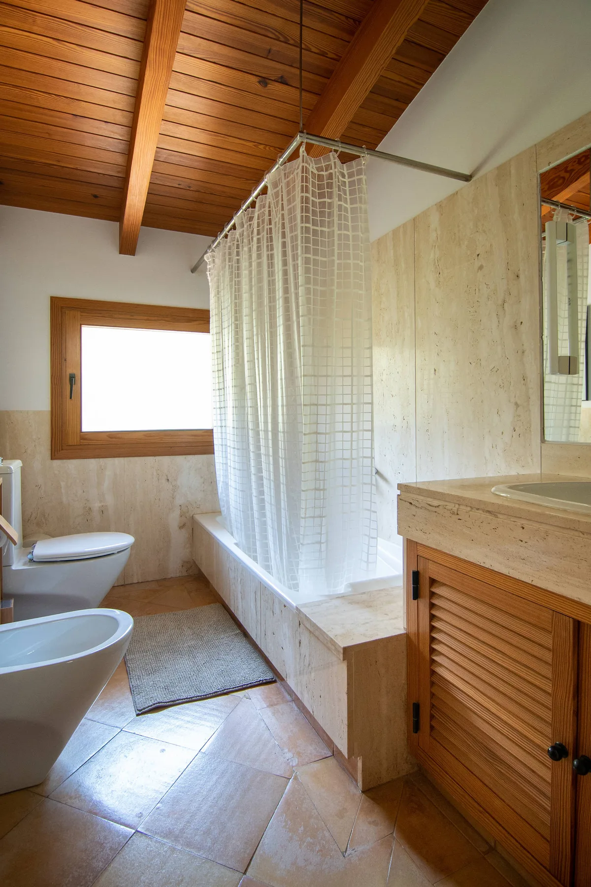 Un baño con bañera, cortina de ducha y mueble de madera.