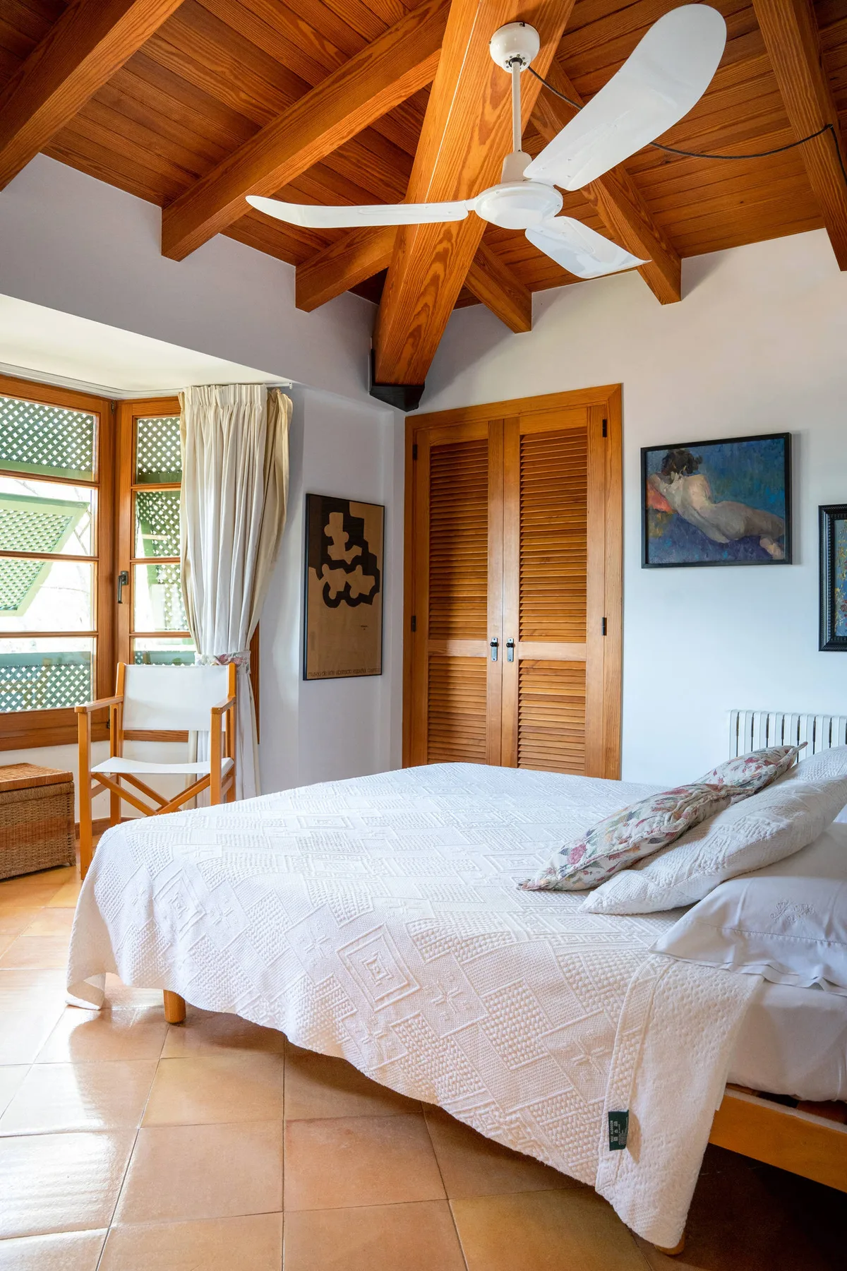 Un dormitorio luminoso con una cama grande bajo un techo de madera.