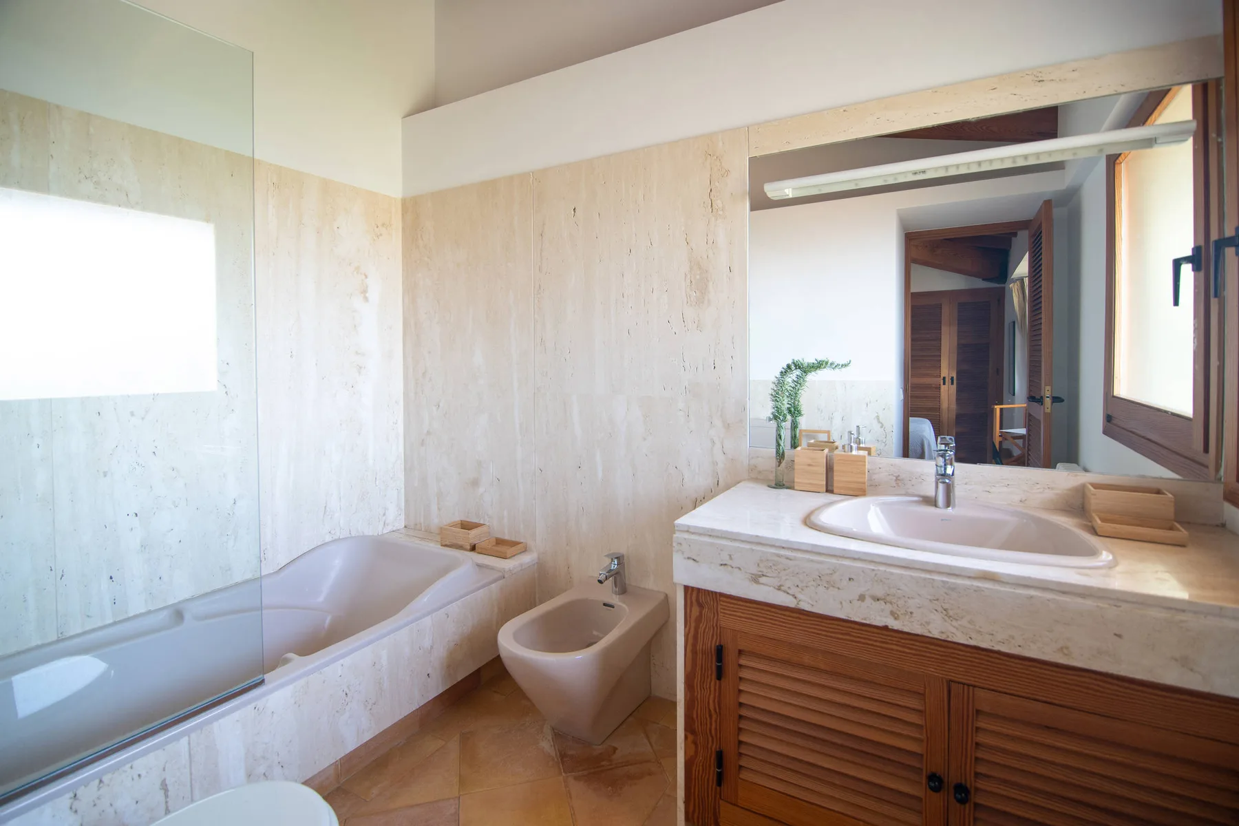 Un baño con bañera, lavabo y un espejo grande.