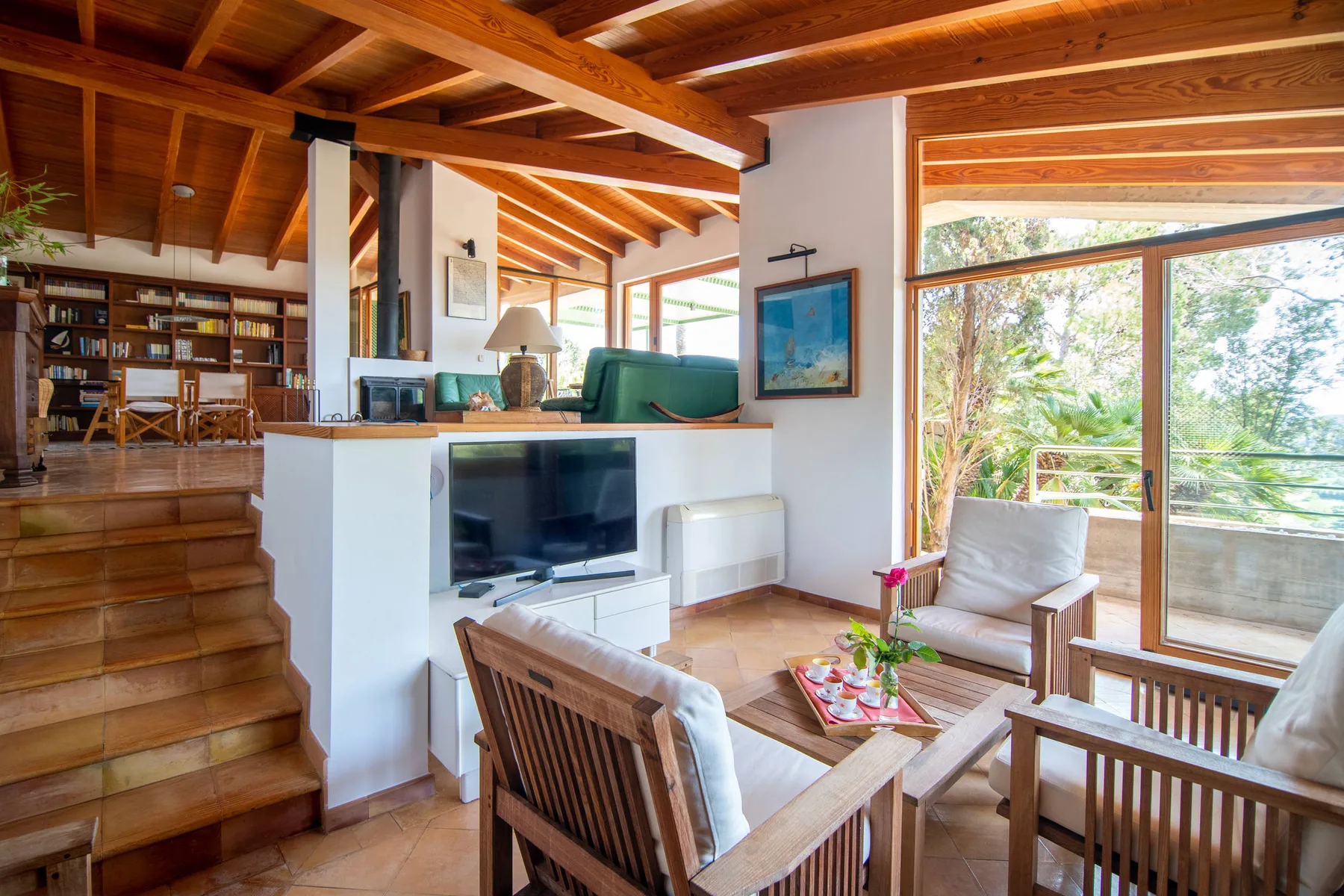 Una sala luminosa con asientos de madera y grandes ventanales con vistas a la vegetación.