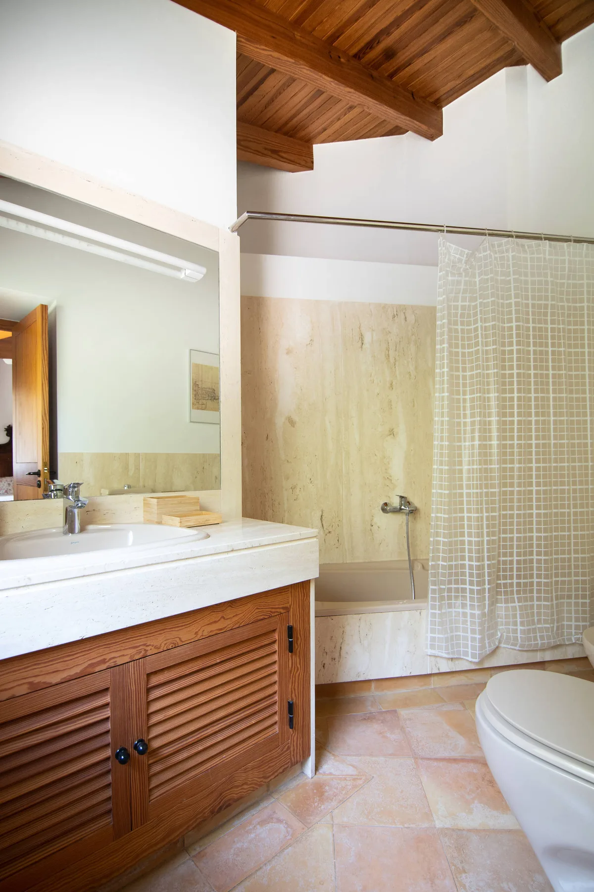 Un baño con mueble de madera, bañera y cortina de ducha.