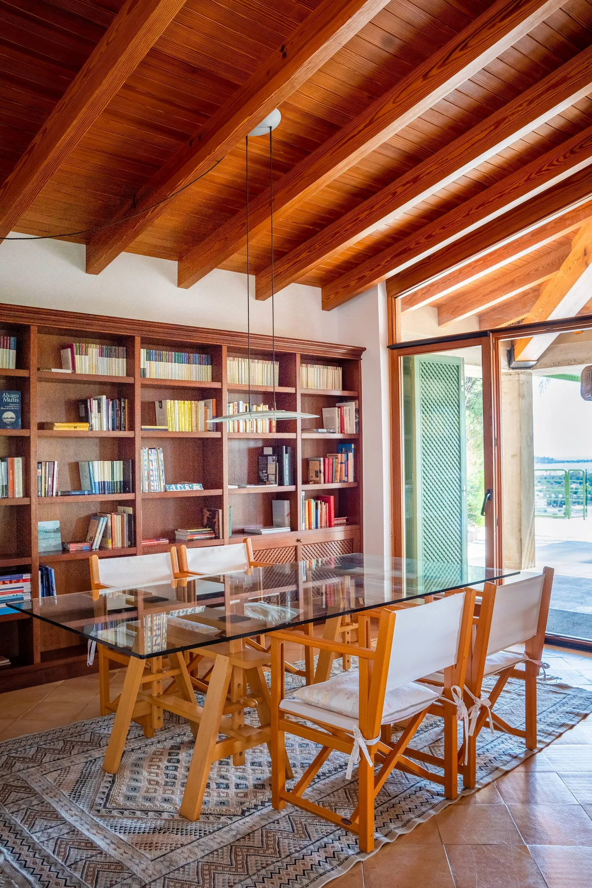 Comedor con una mesa de madera y sillas frente a estanterías empotradas.