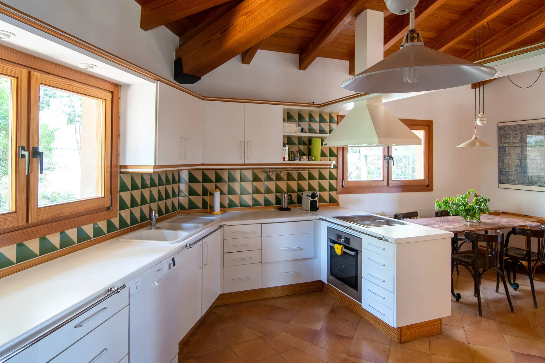 Una cocina luminosa con armarios blancos, azulejos estampados y una isla central.