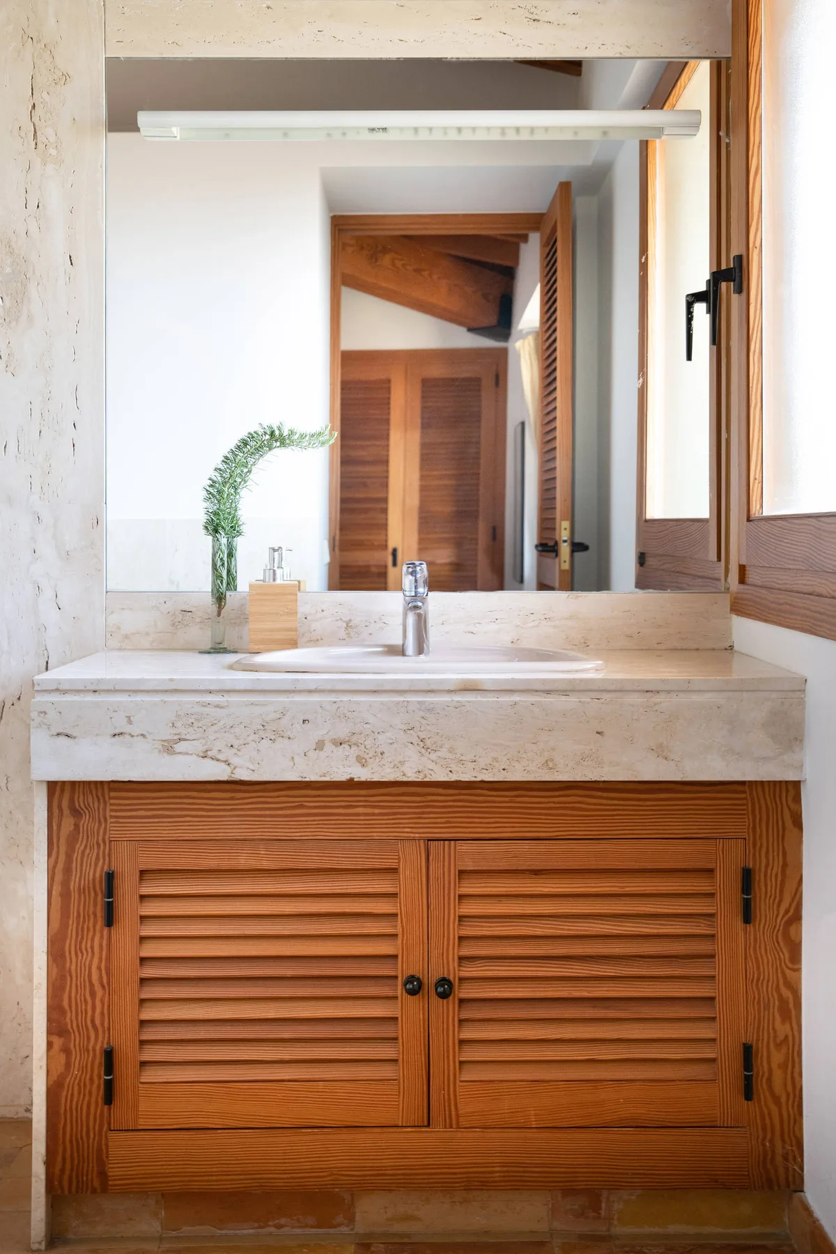 Un lavabo de baño con un espejo amplio y puertas de madera.