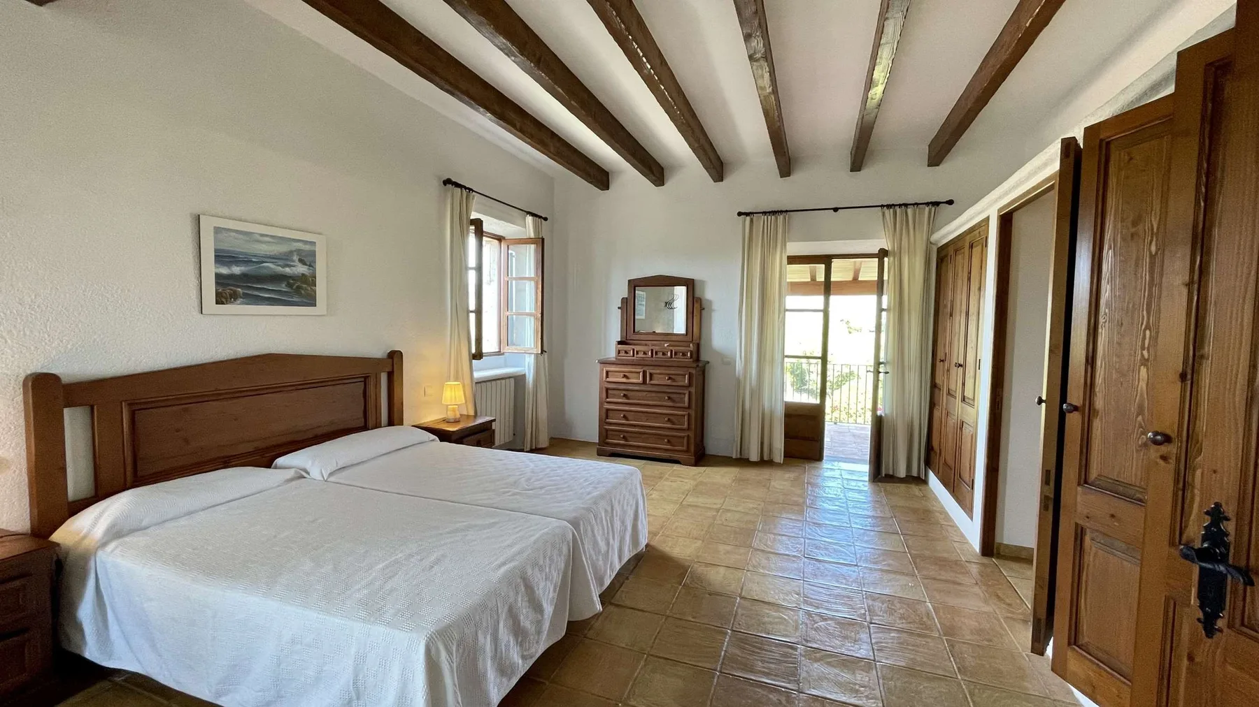 Un dormitorio con dos camas, armarios de madera y vigas vistas en el techo.