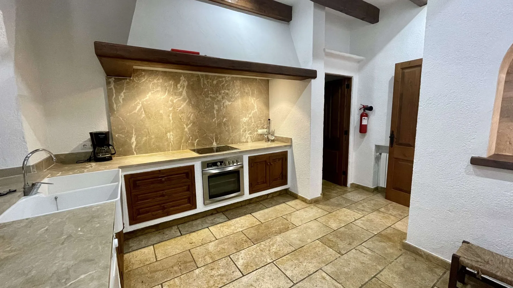 Una cocina con gabinetes de madera, una encimera y un suelo de baldosas.