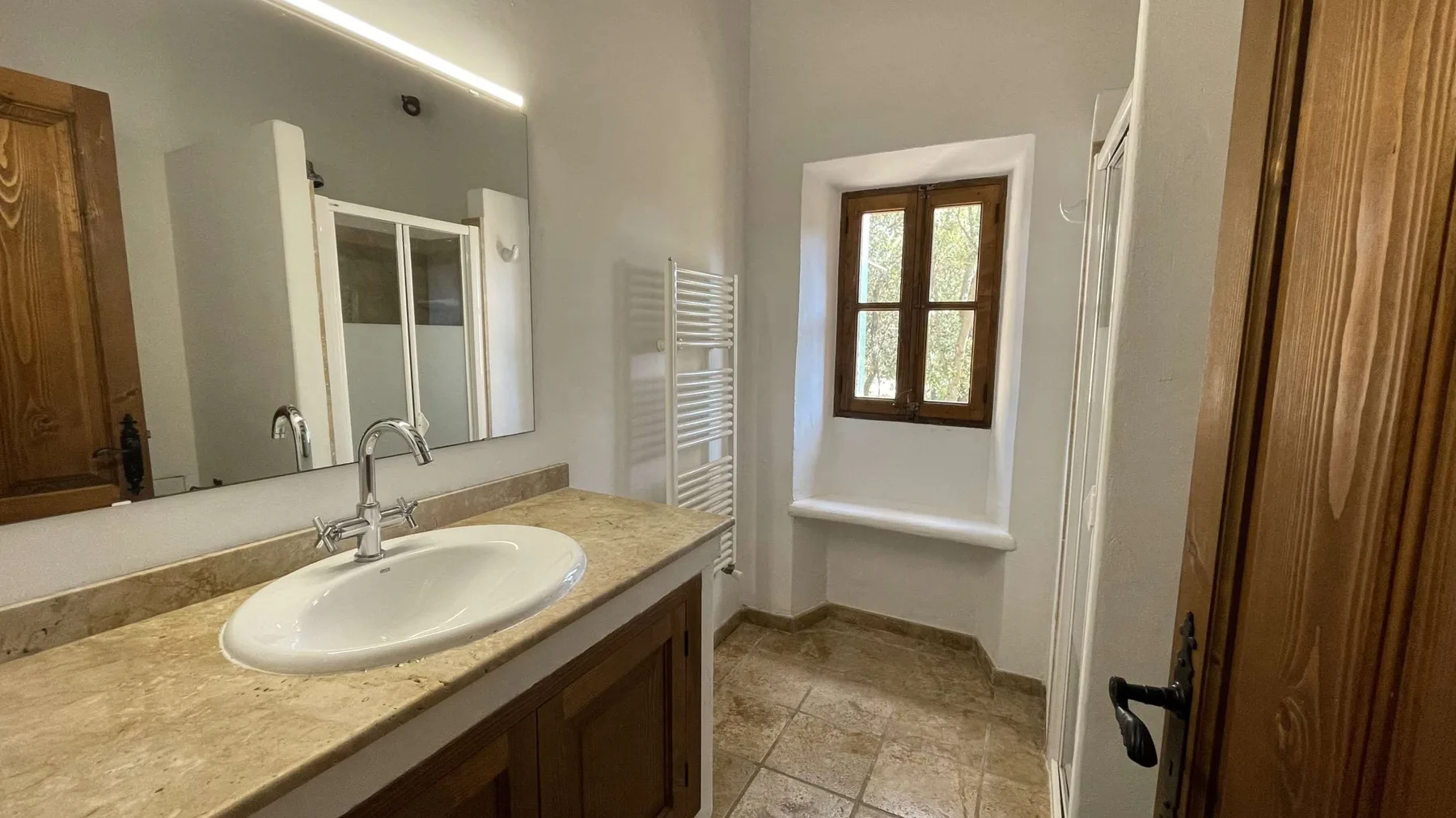 Un baño con lavabo, espejo y ventana.