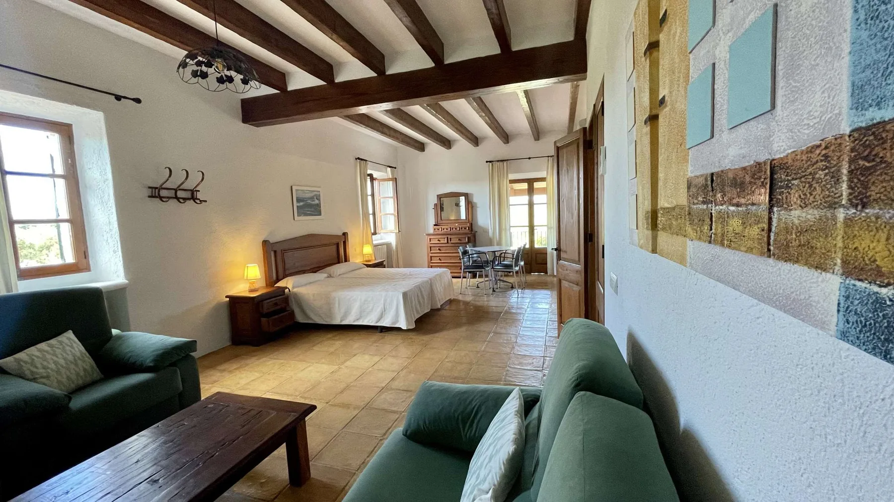 Un dormitorio con una cama, asientos y vigas expuestas en el techo.