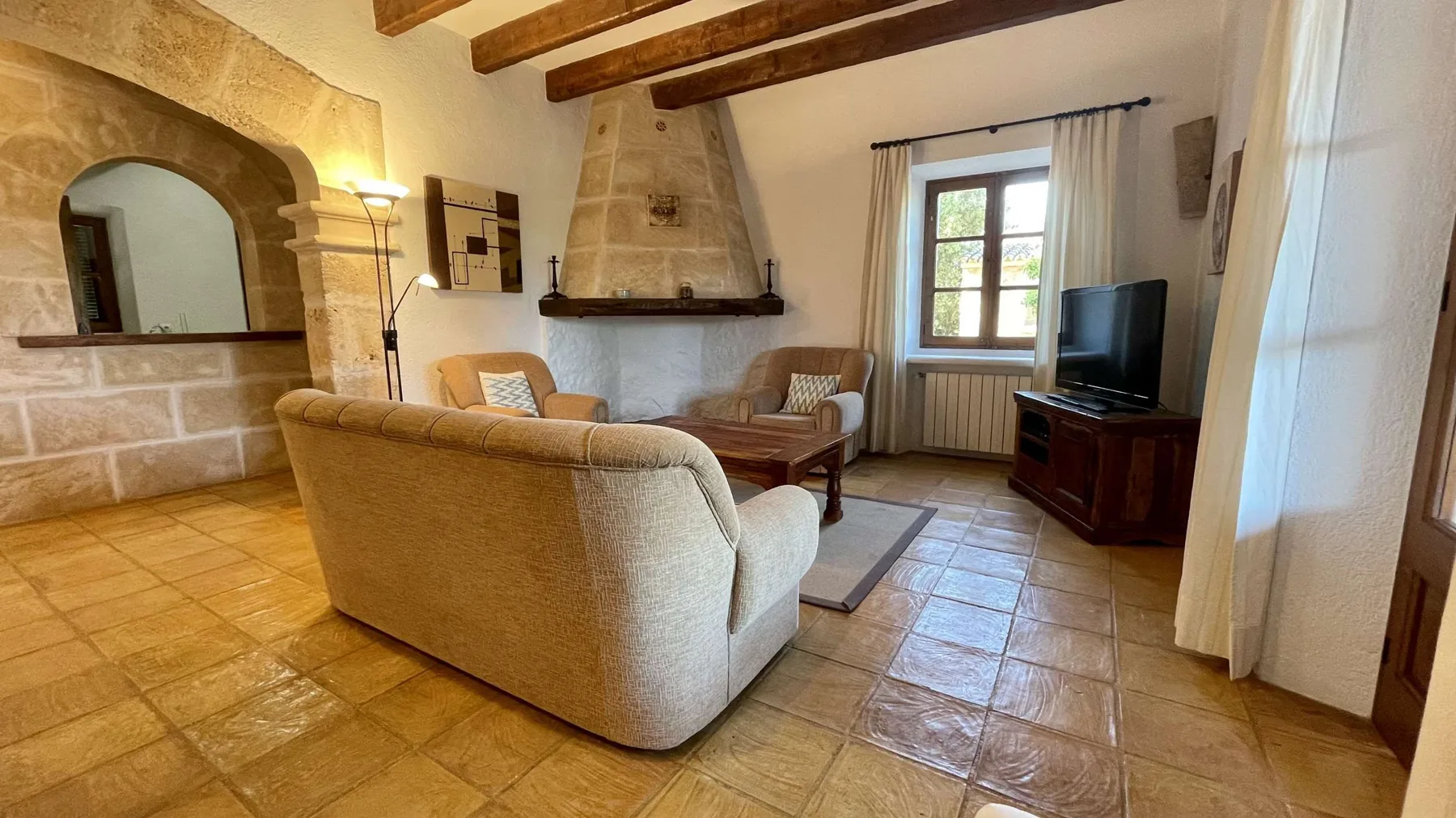 Una sala de estar con asientos, una chimenea de piedra y un televisor.
