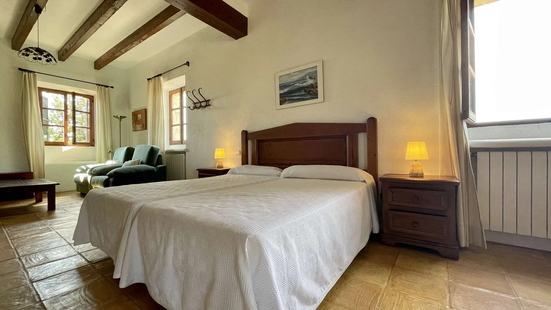 Un dormitorio con una cama bien tendida, mesitas de noche y una zona de estar.