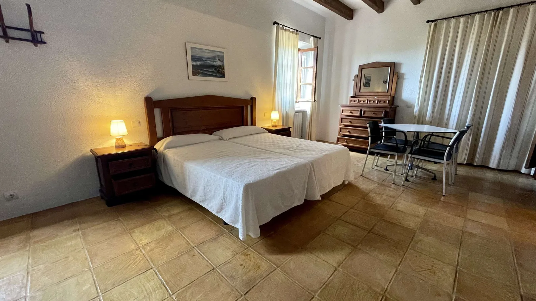 Un dormitorio con una cama doble, mesitas de noche y una pequeña zona de comedor.