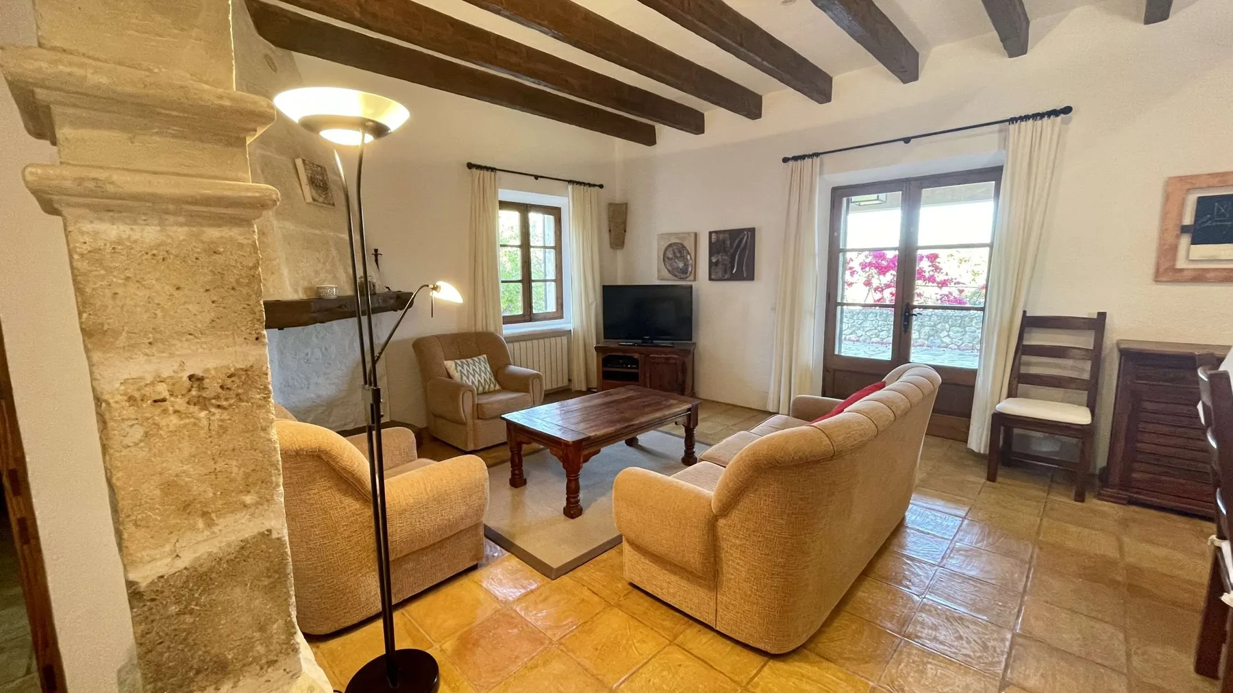 Una sala de estar con asientos, una mesa de centro y vigas a la vista.