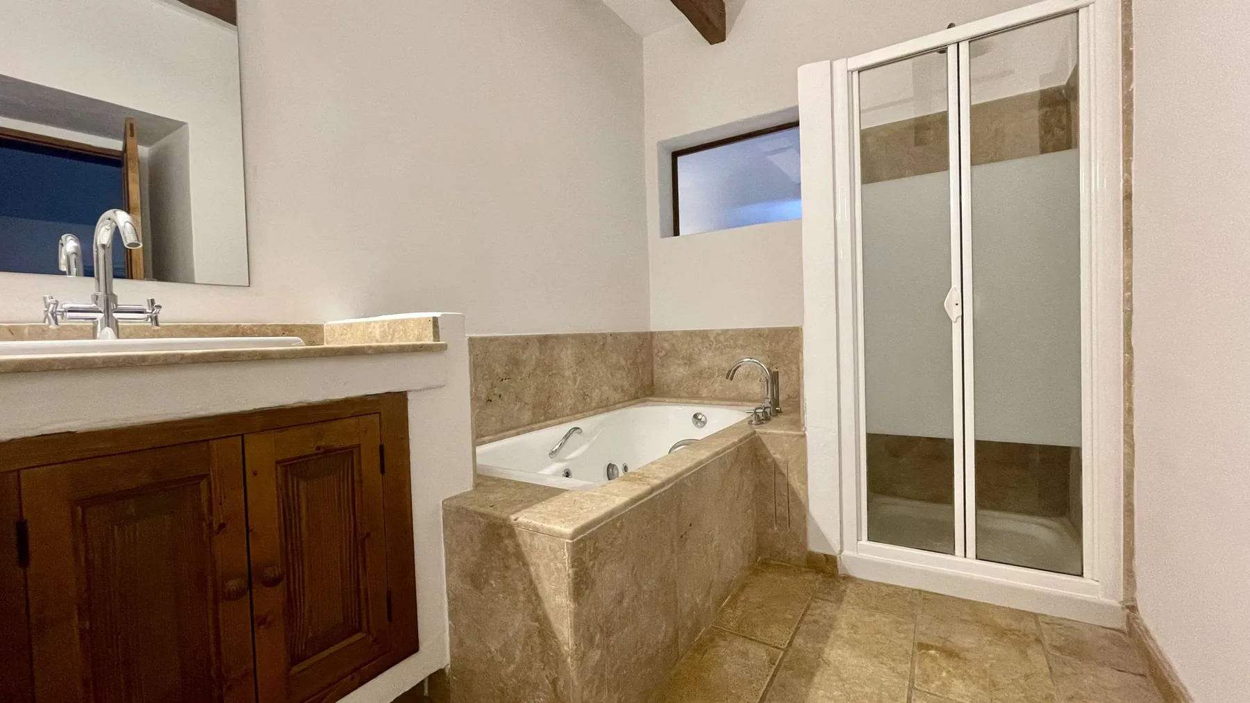 Un baño con bañera, lavabo y mampara de ducha de vidrio.