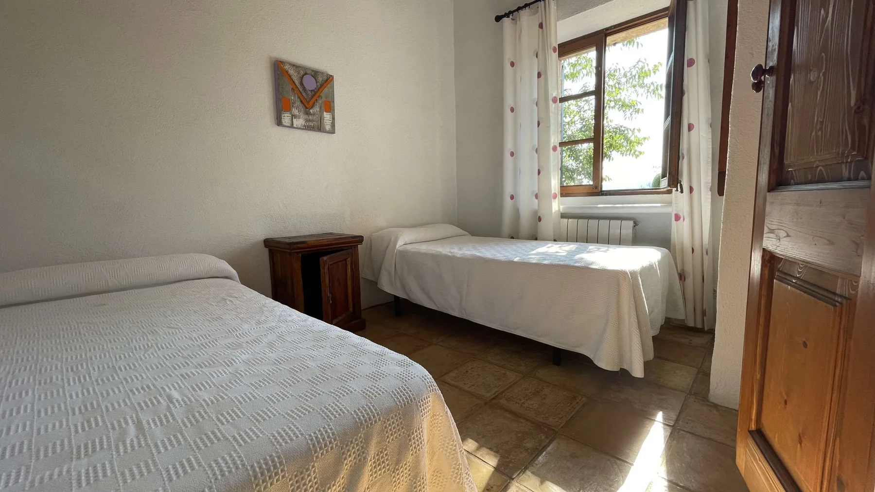 Un dormitorio con dos camas junto a una ventana con cortinas.