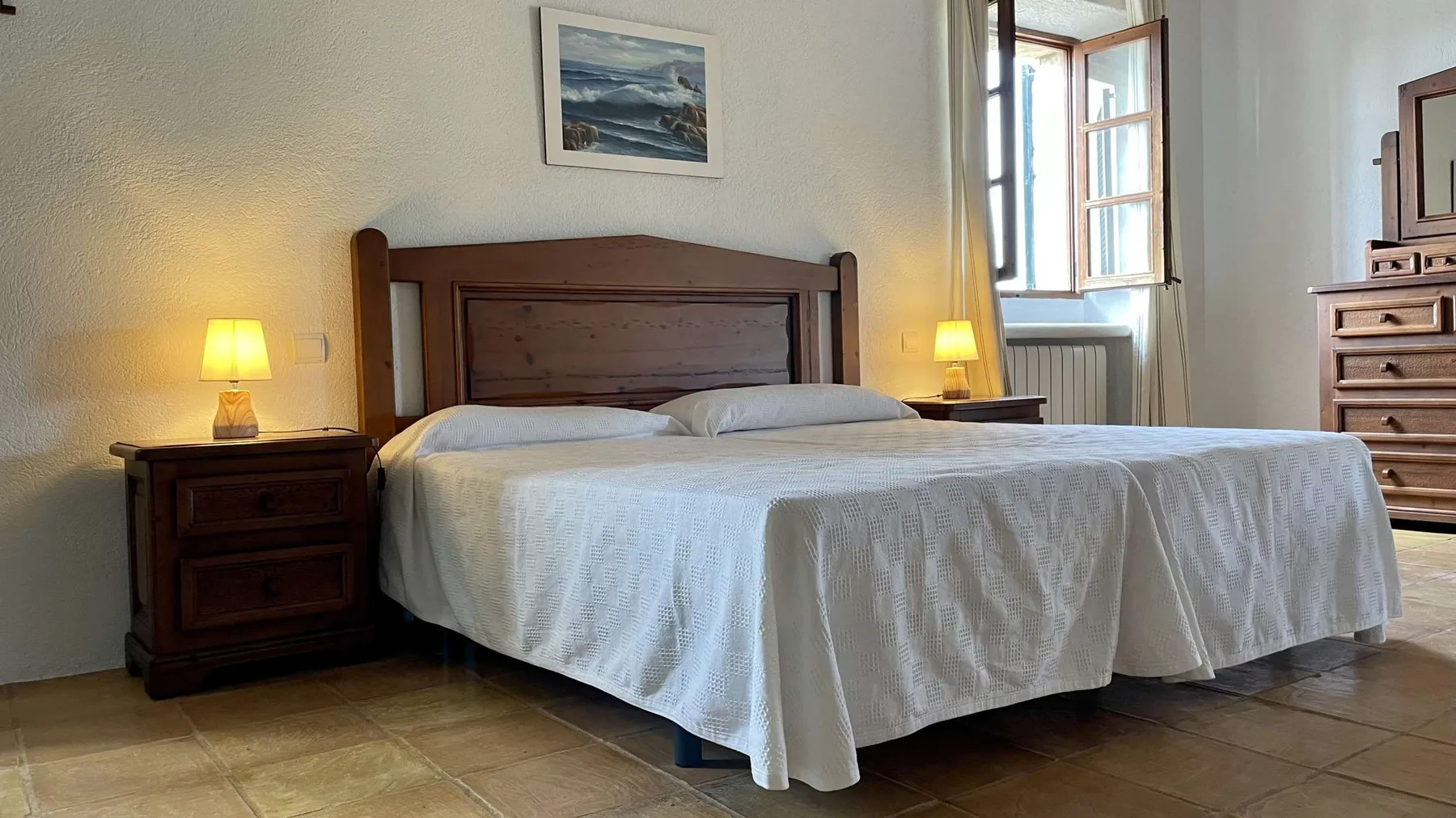 Un dormitorio con una cama doble, mesitas de noche y una ventana.
