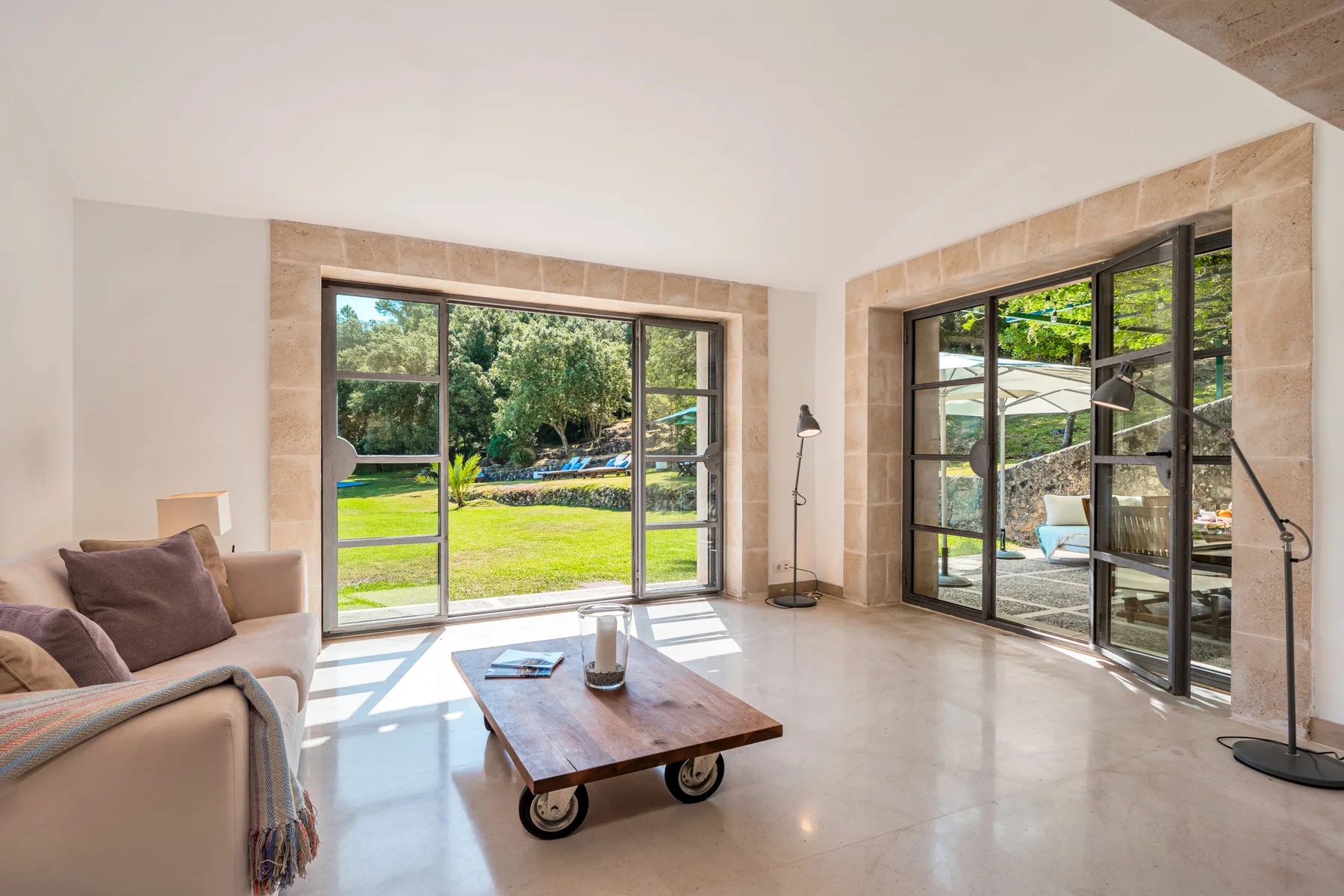 Una sala luminosa se abre al jardín a través de grandes puertas de vidrio.