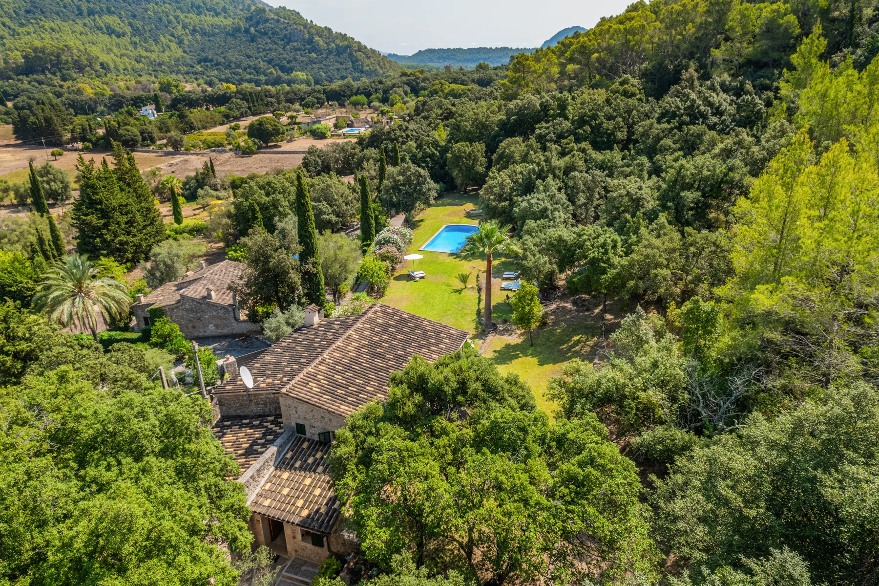 Vista aérea de una propiedad arbolada con una casa y una piscina.