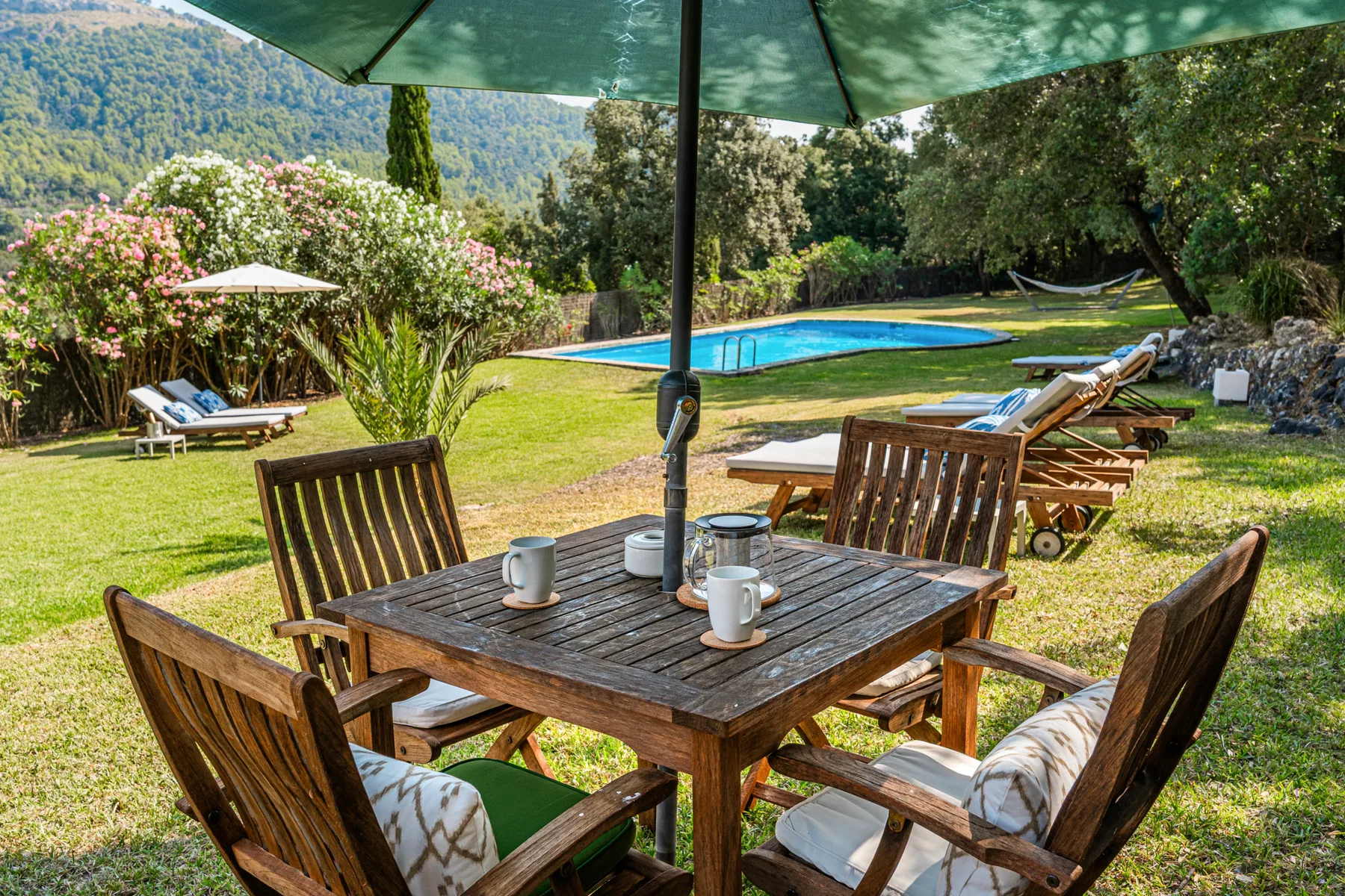Una zona de comedor al aire libre da a una piscina y un jardín.