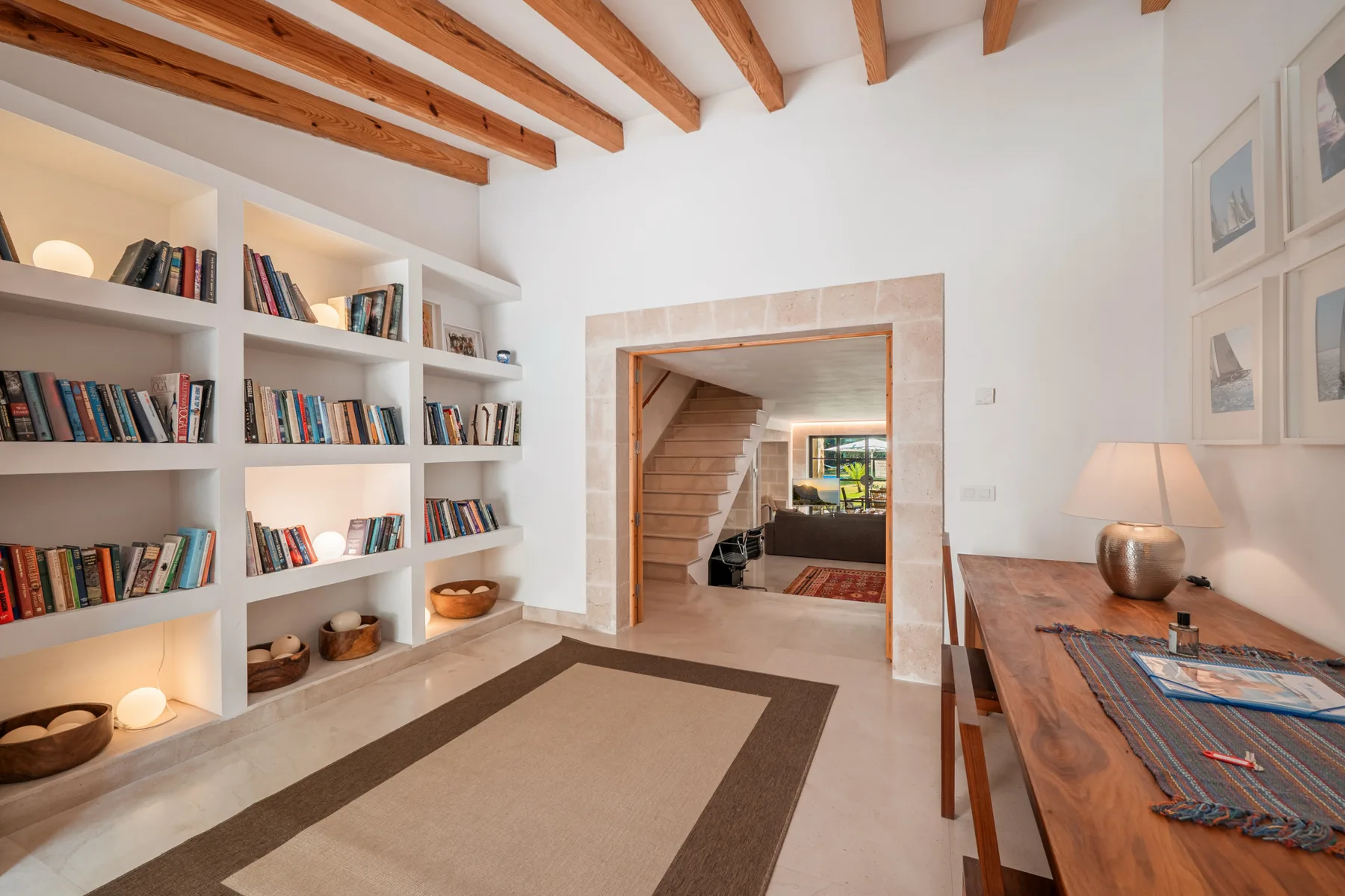 Una sala luminosa con estanterías empotradas y una mesa de madera.