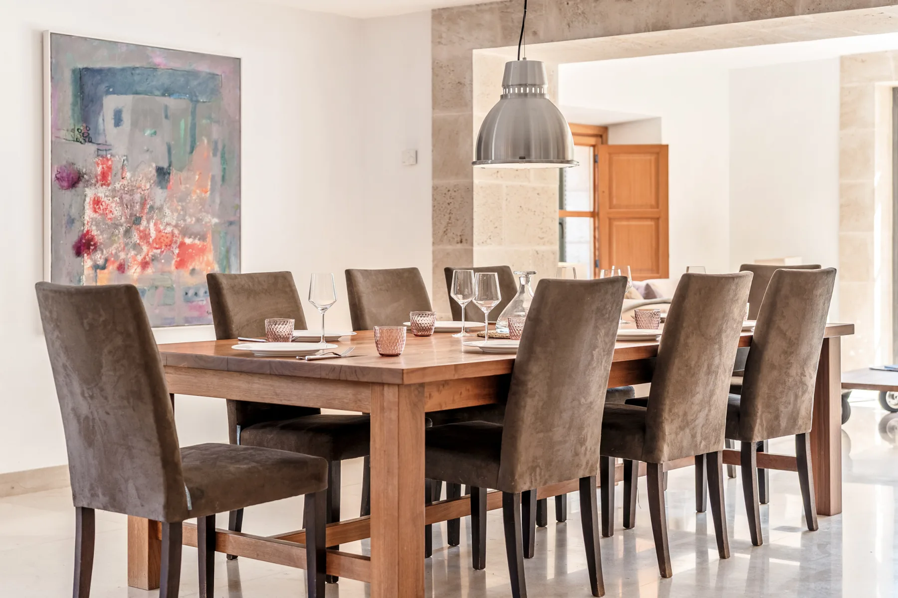 Comedor con una mesa de madera, asientos tapizados y una lámpara colgante.