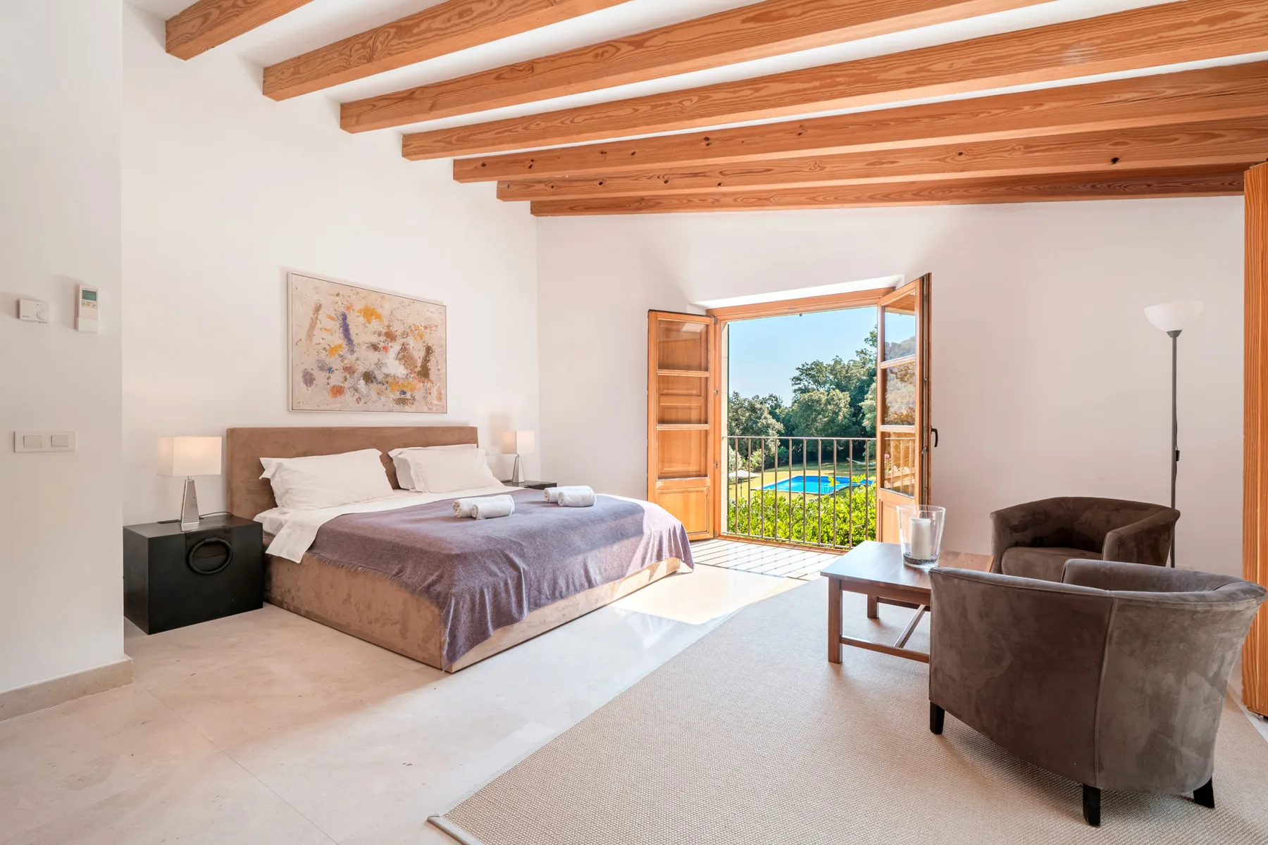 Un dormitorio con una cama doble y una puerta abierta hacia un balcón.