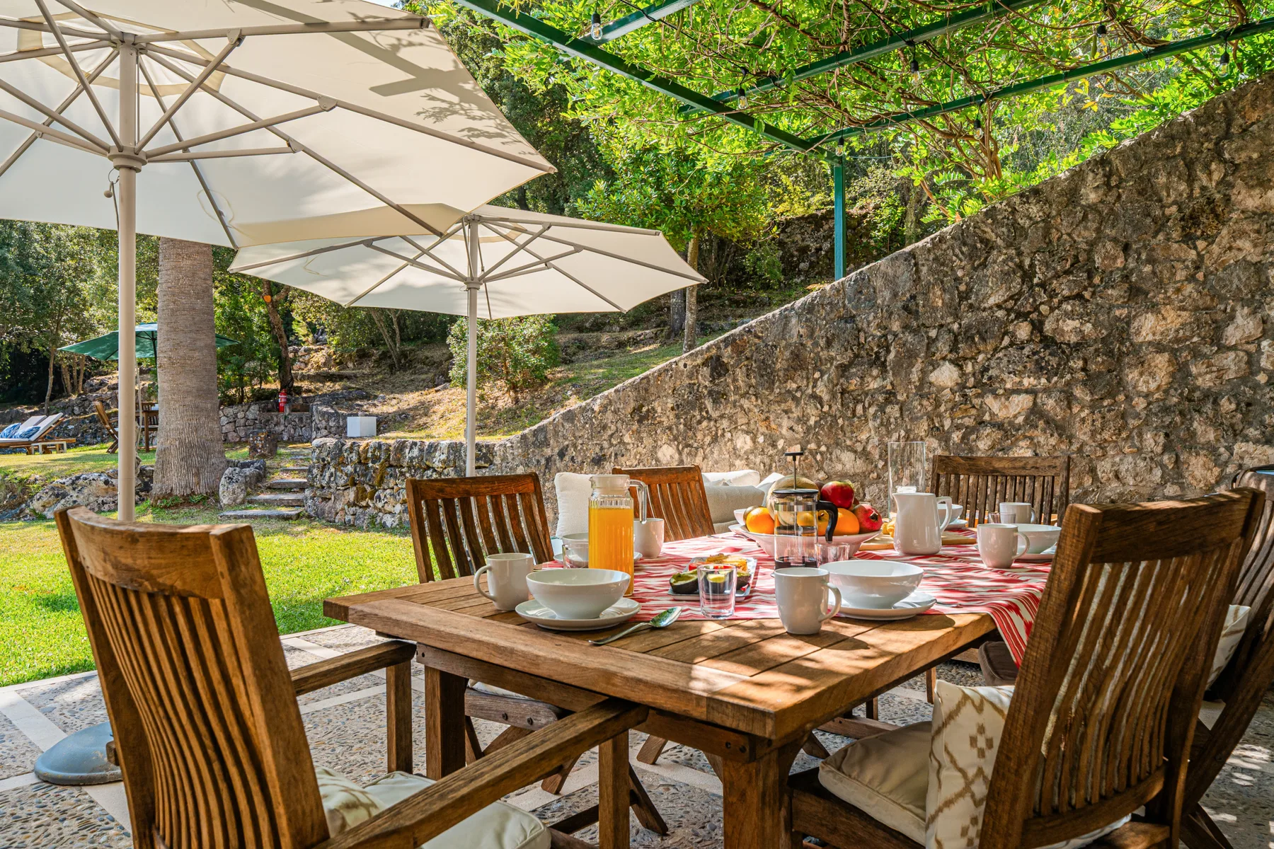 Un comedor al aire libre con una mesa de madera bajo grandes sombrillas.