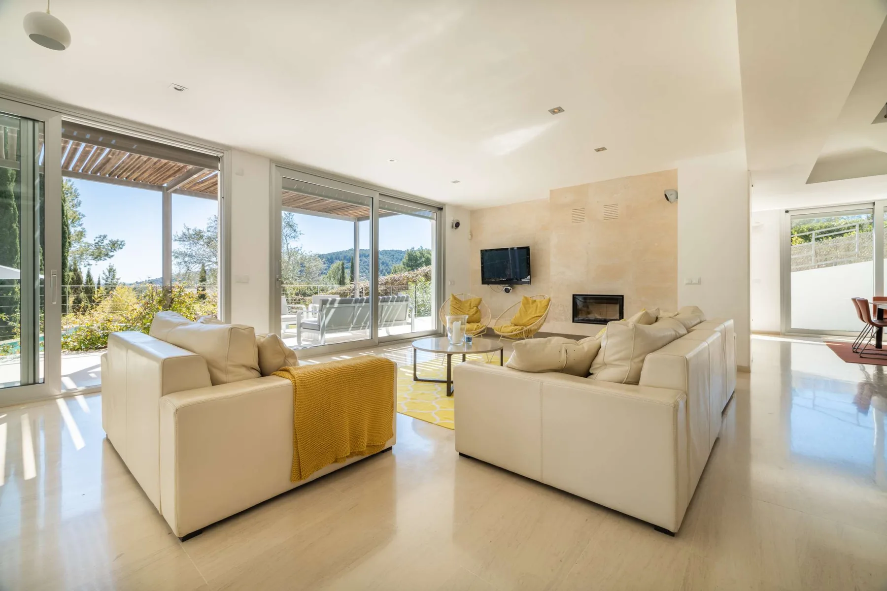 A bright living room with cream seating, a fireplace, and large windows.