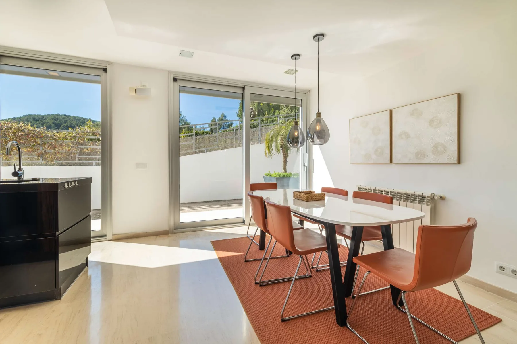 A bright dining area with a table and chairs beside large windows.