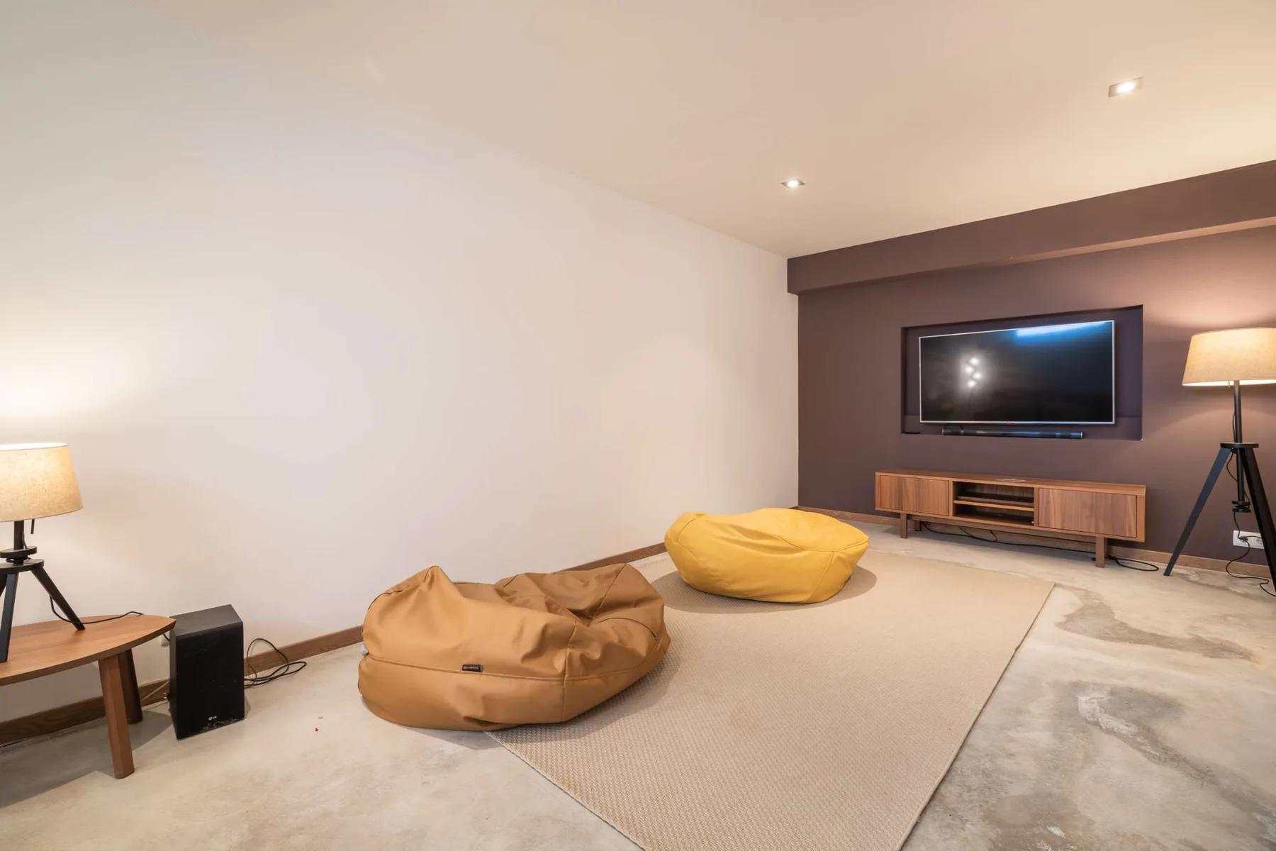 A lounge with a wall-mounted television and beanbag seating.