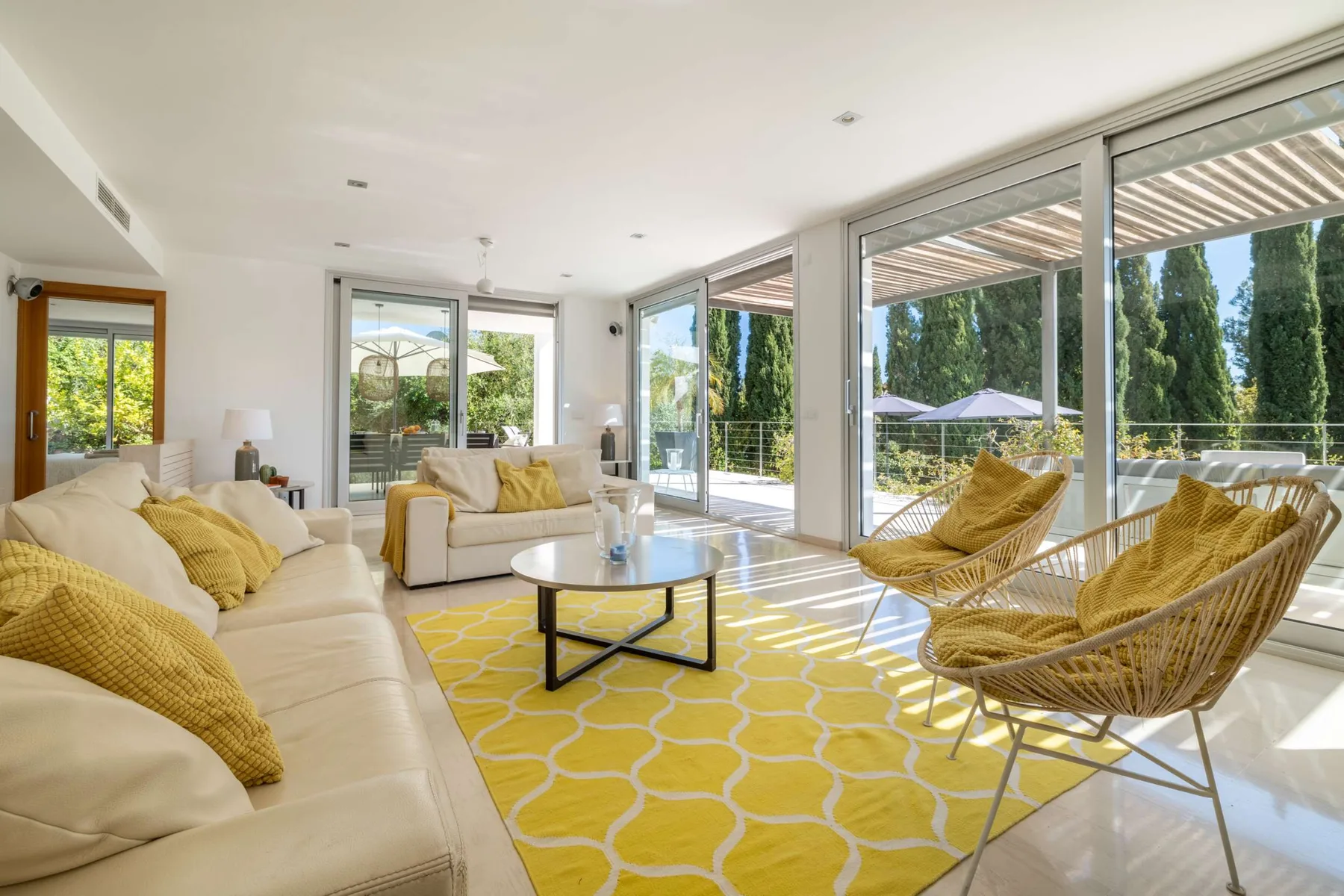 A bright living room opens onto a patio, with seating around a coffee table.