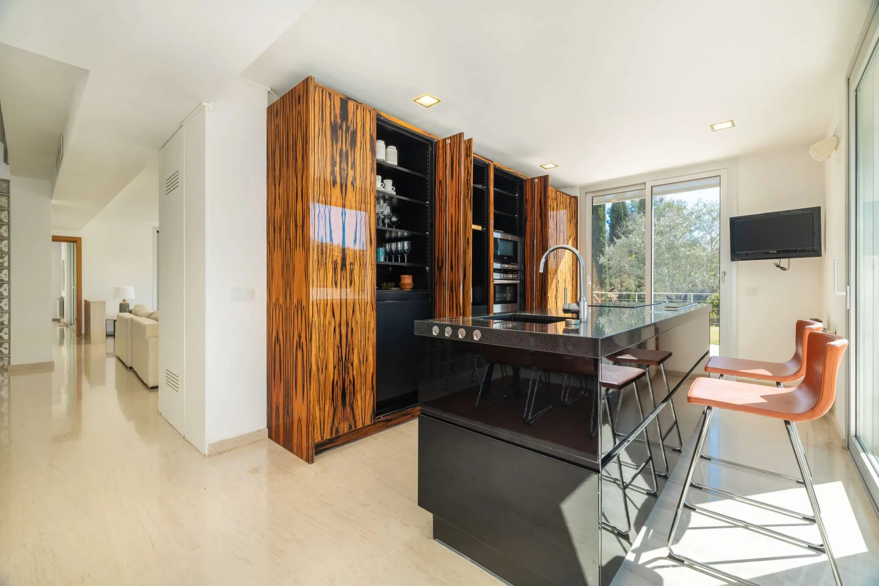 A bright kitchen with a dark island and bar seating beside large windows.