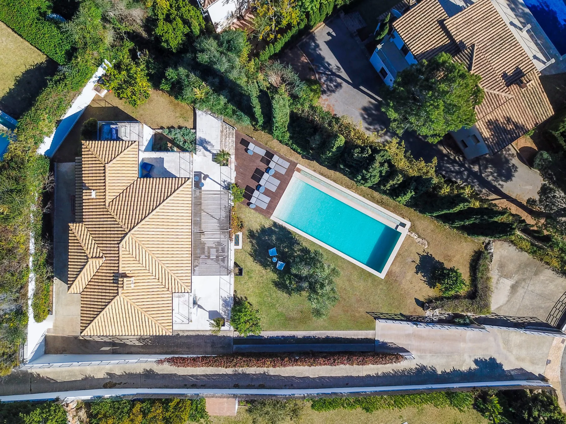An aerial view shows a house, a rectangular swimming pool, and surrounding greenery.