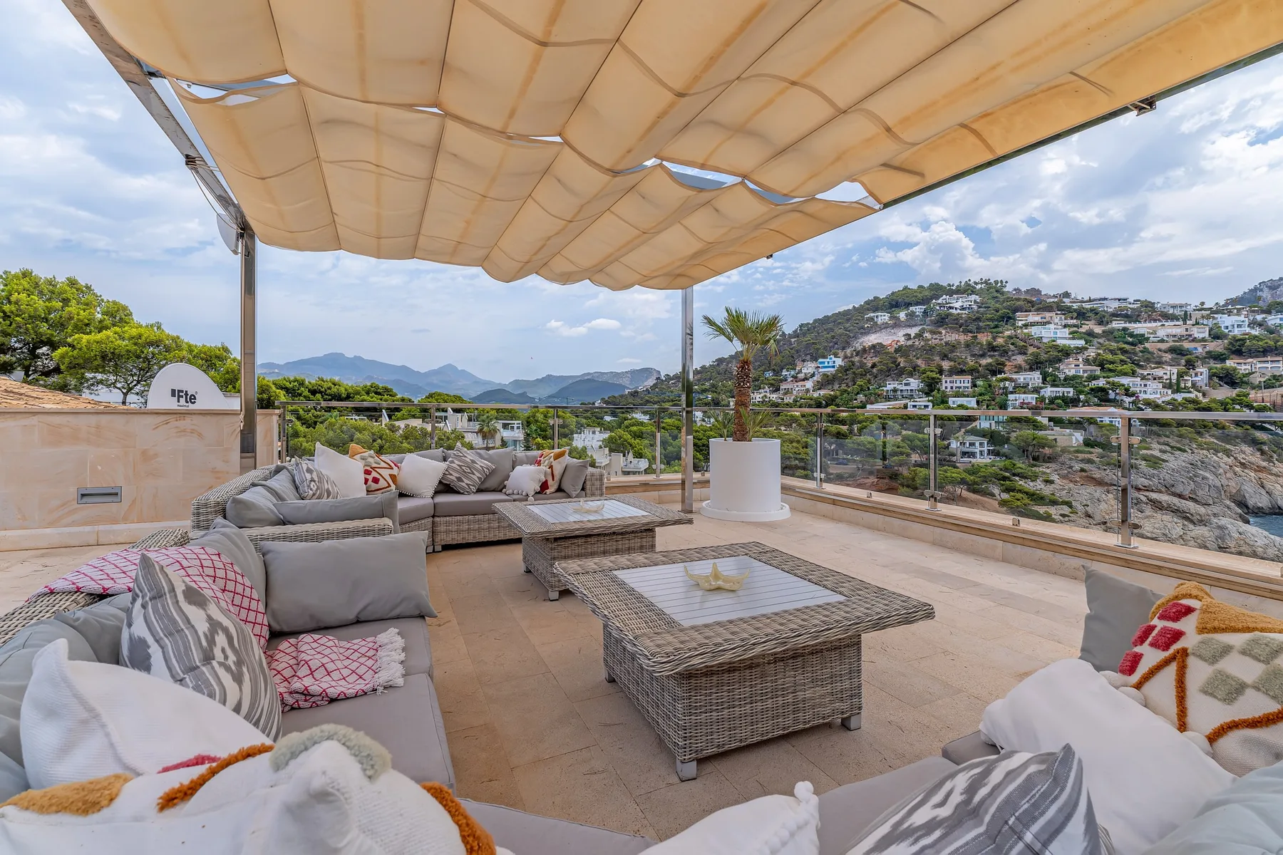 An outdoor terrace with cushioned seating and a view of the surrounding hills.