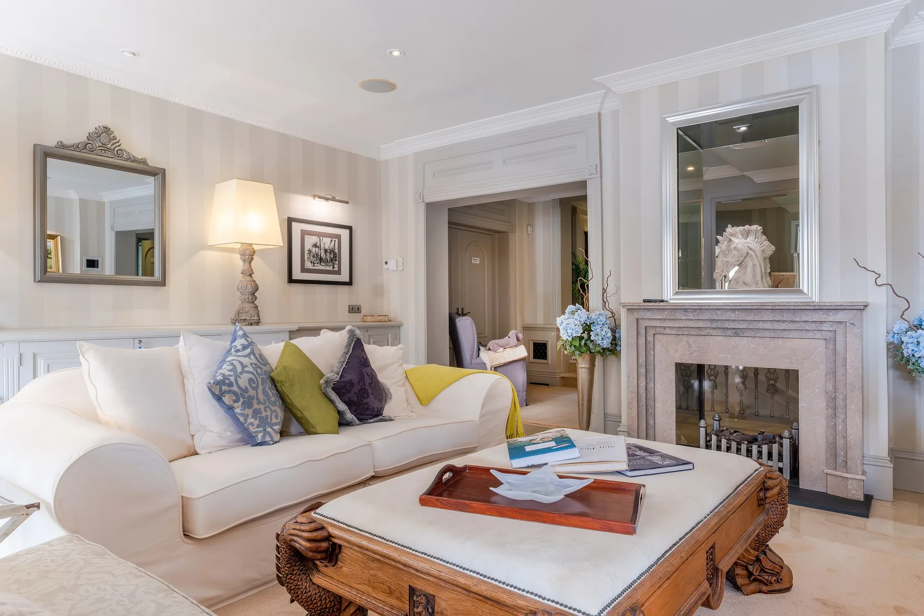 A bright living room with seating, a coffee table, and a fireplace.