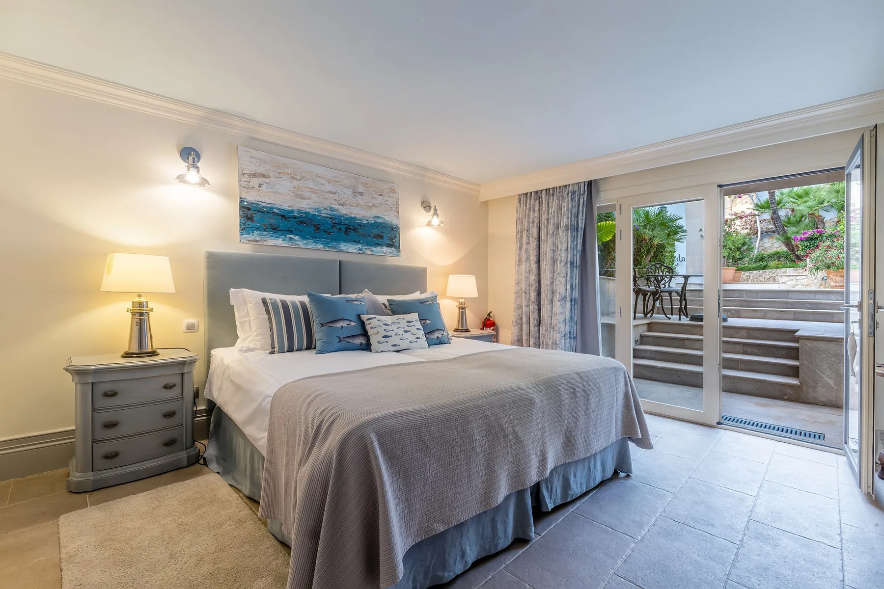 A bedroom with a neatly made bed and glass doors opening onto a patio.