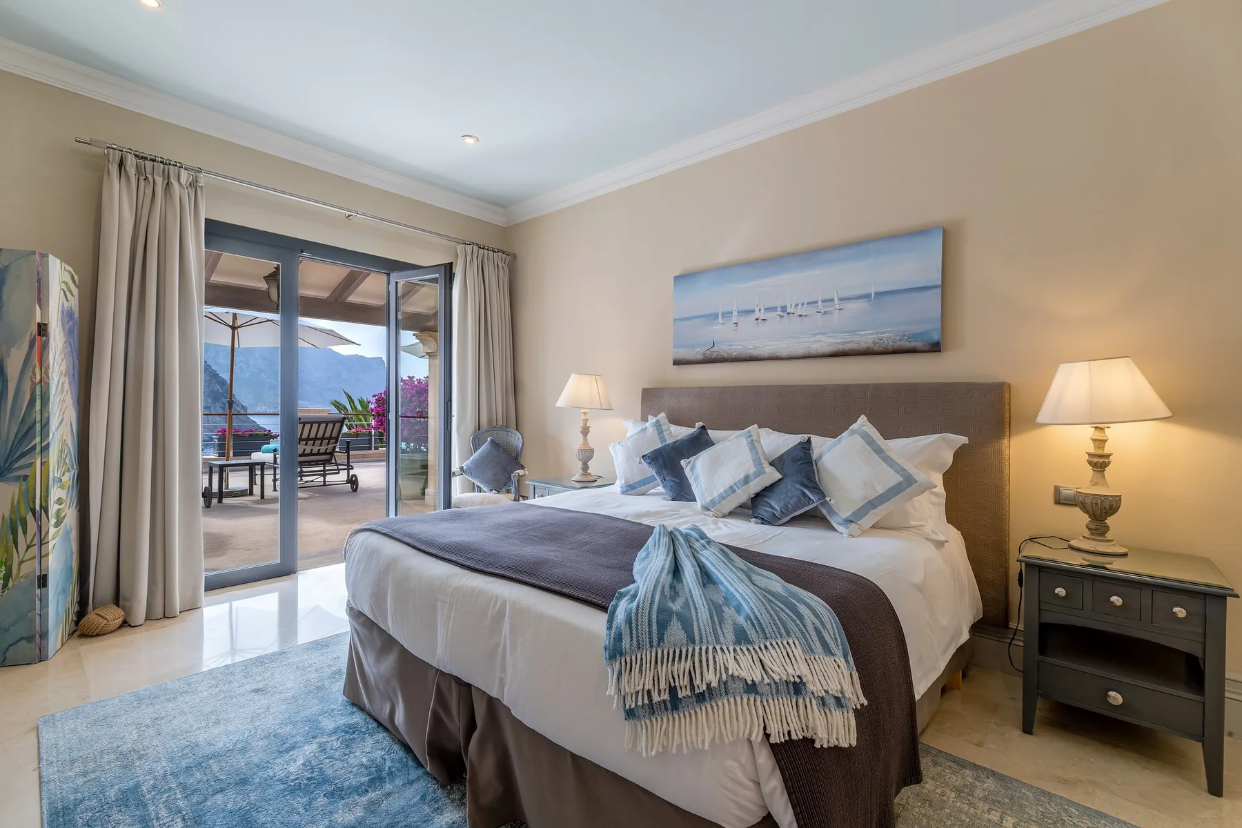 A bedroom with a large bed, bedside tables, and sliding glass doors opening onto a patio.