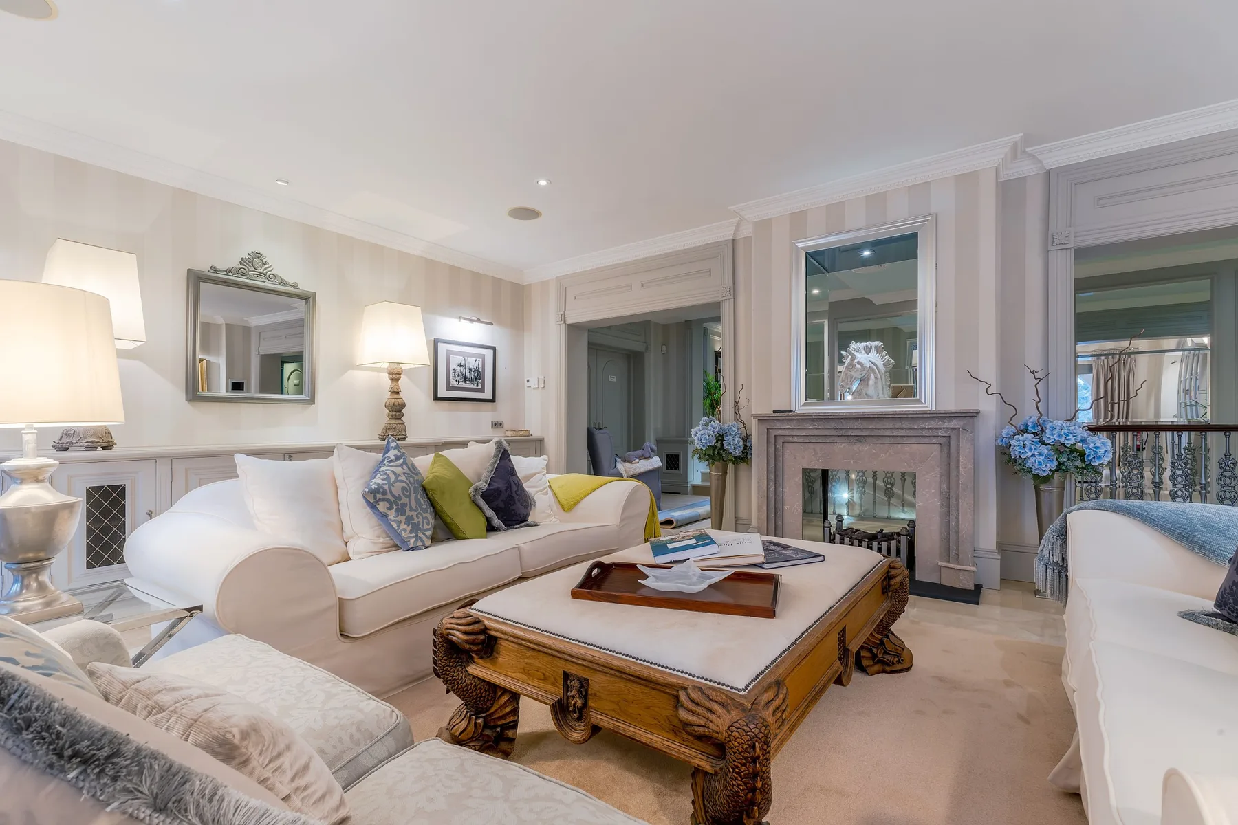 A bright living room with upholstered seating arranged around a carved wooden coffee table.