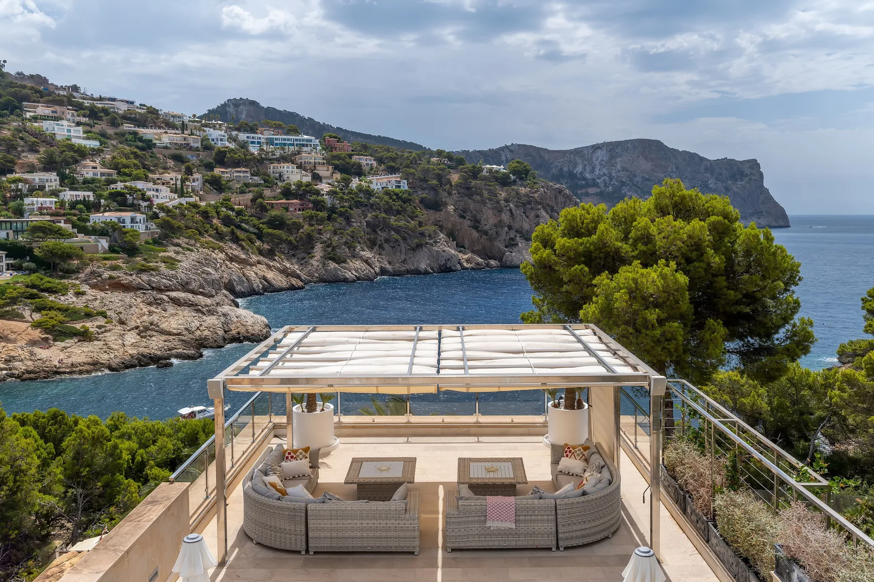 A covered outdoor seating area overlooks the sea and rocky coastline.