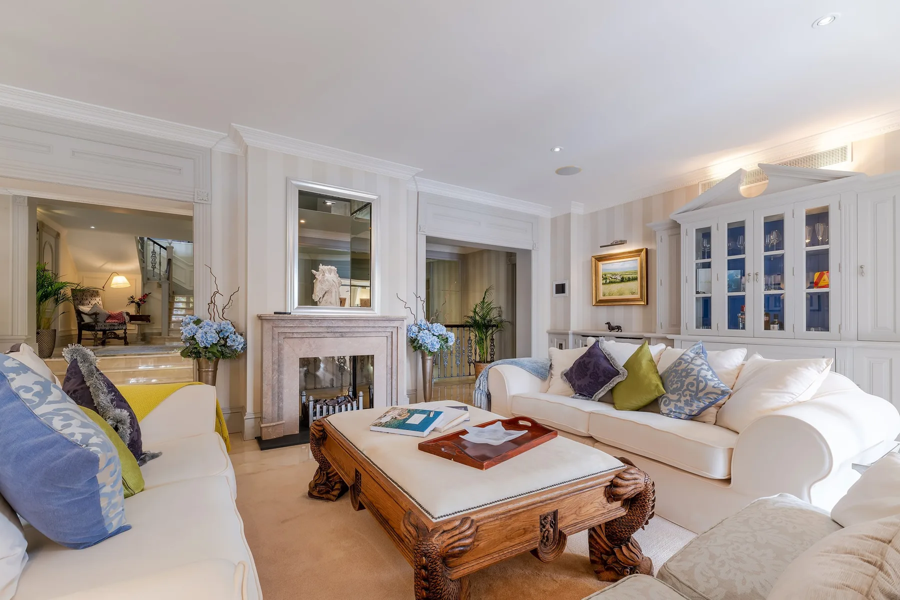A bright living room with upholstered seating arranged around a coffee table and fireplace.