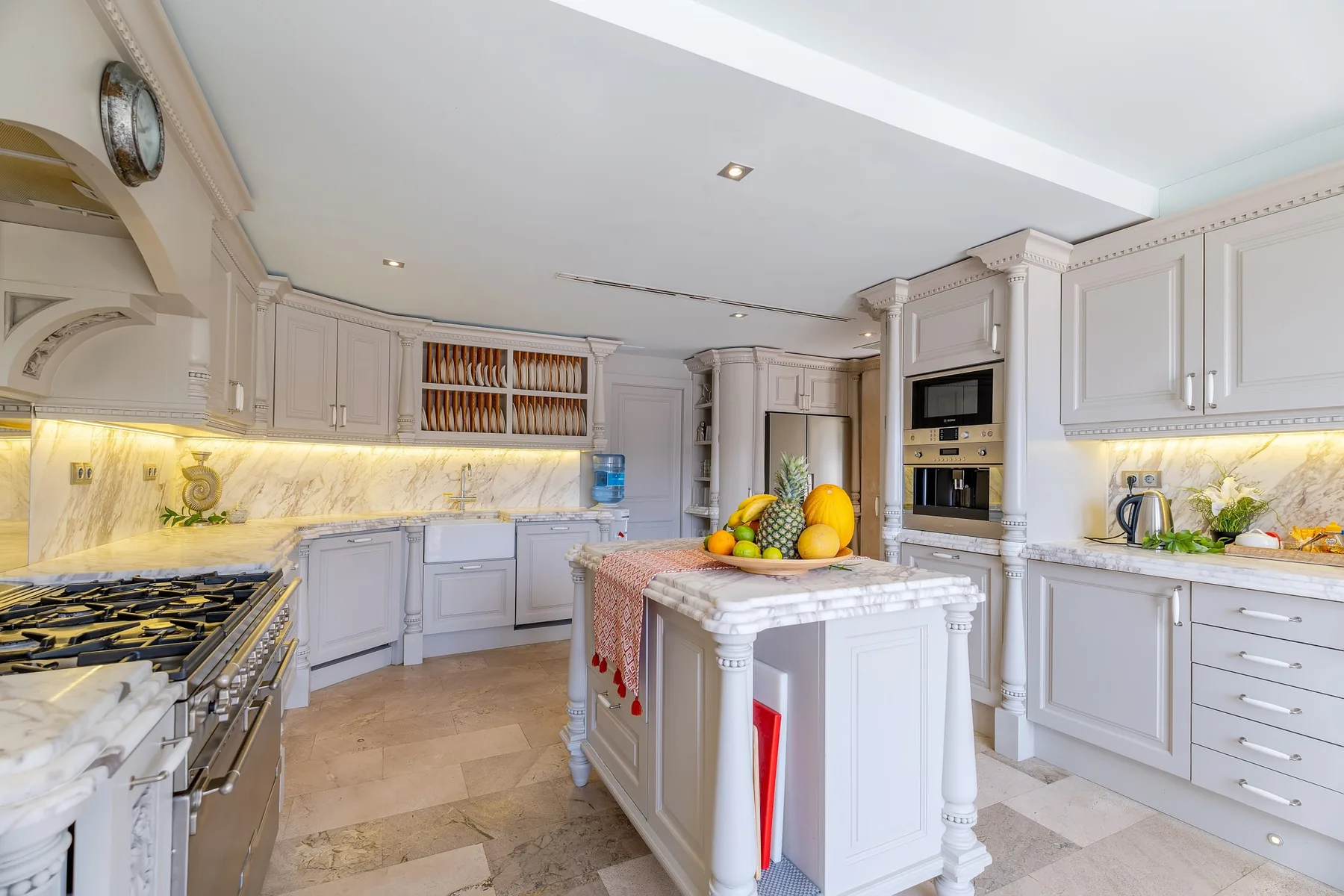 A bright kitchen with white cabinetry, stone counters, and a central island.
