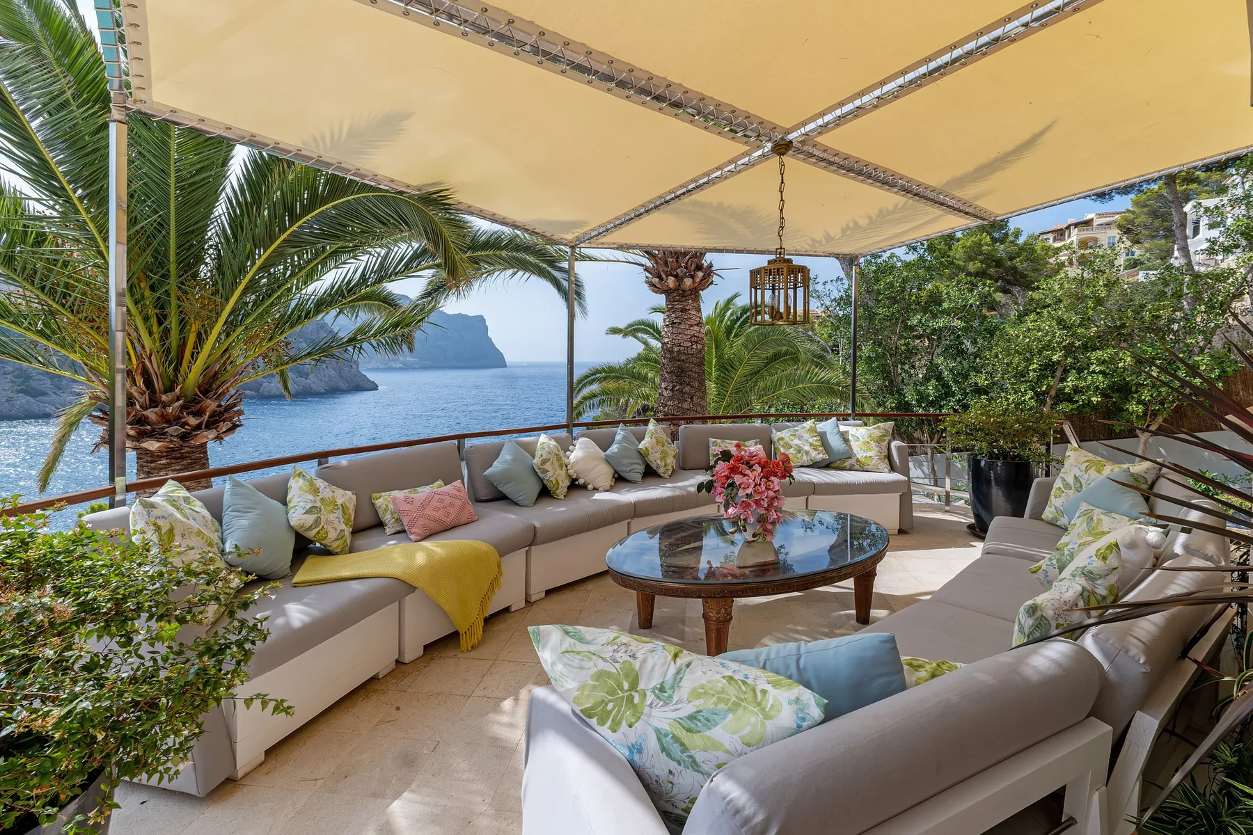An outdoor lounge with cushioned seating and a view of the sea.